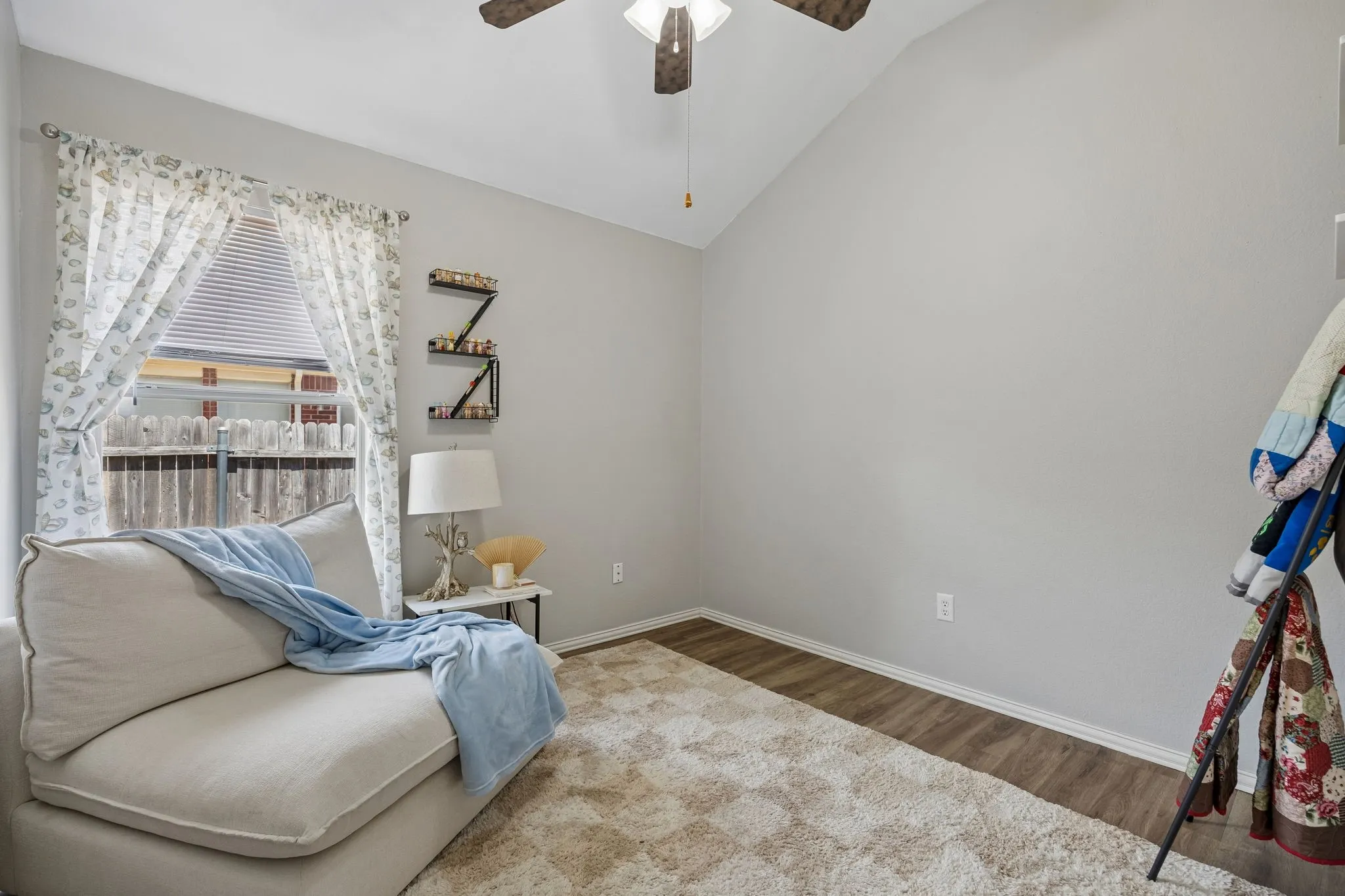 Vaulted ceiling with a ceiling fan, window with blinds, and wood-finish flooring