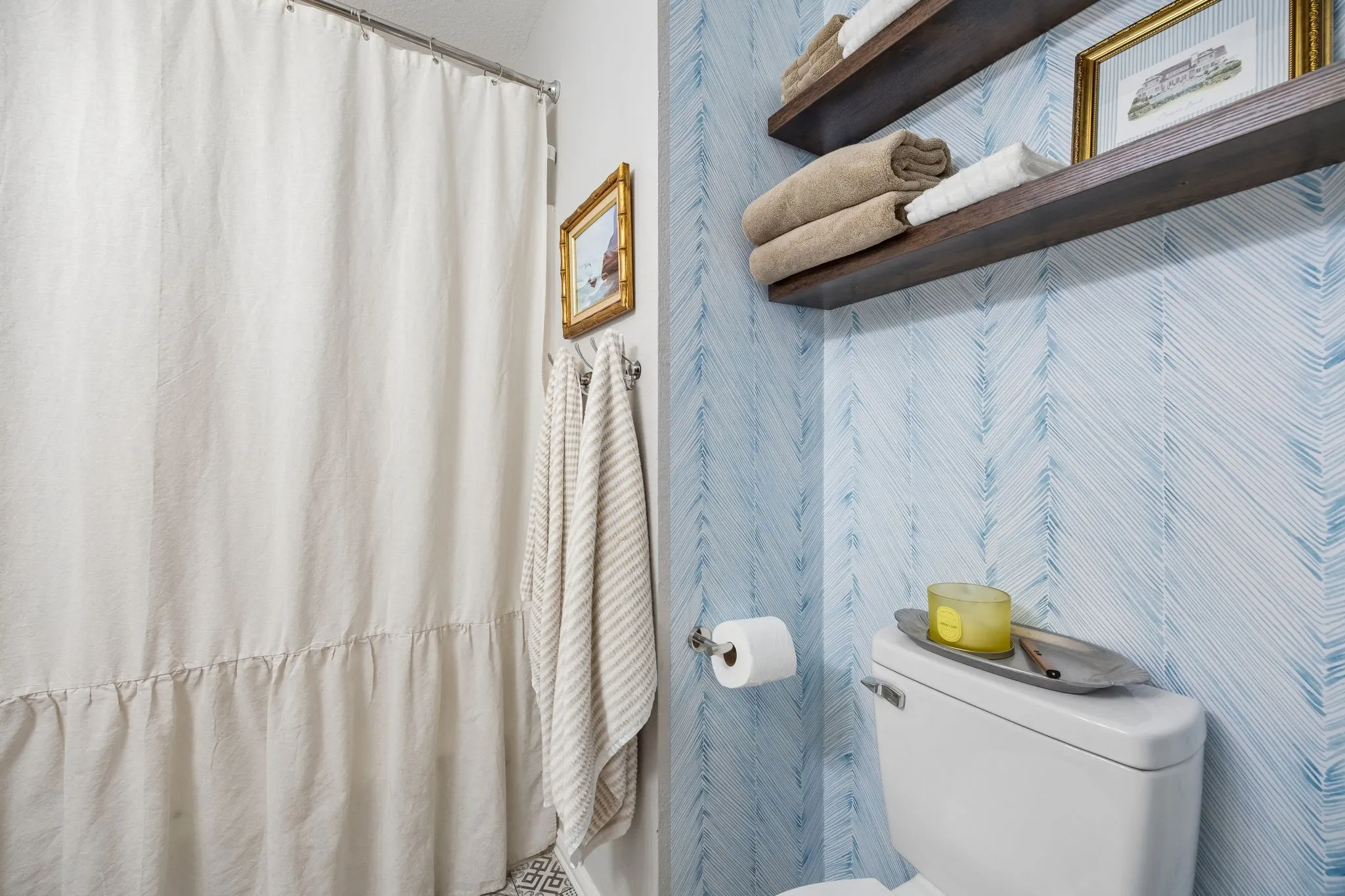 Wall-mounted toilet paper holder, two floating wood shelves, and patterned wall covering