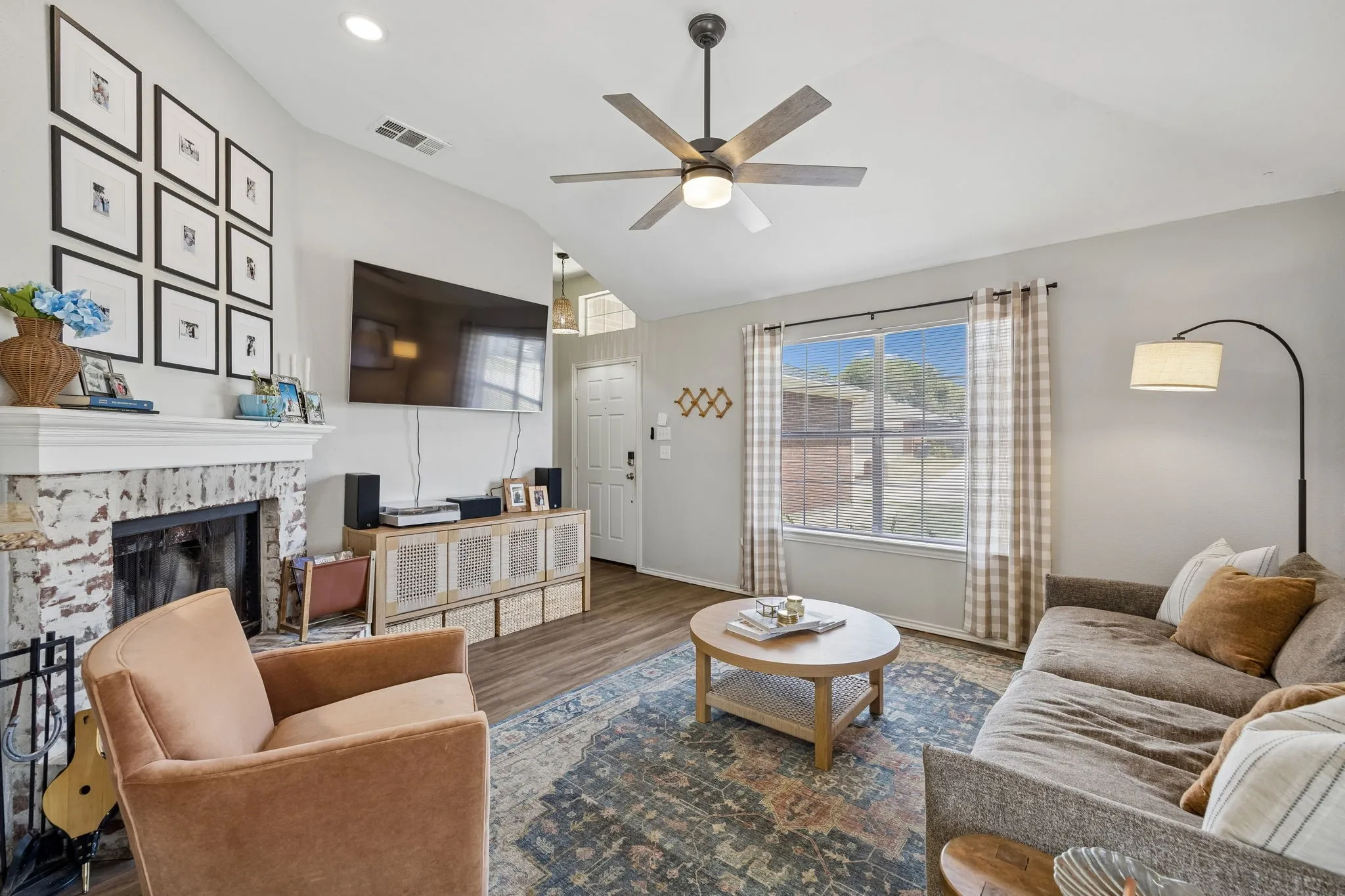 Bright, open living space featuring hardwood flooring, a wood-burning fireplace with decorative tile surround, and built-in cabinetry
