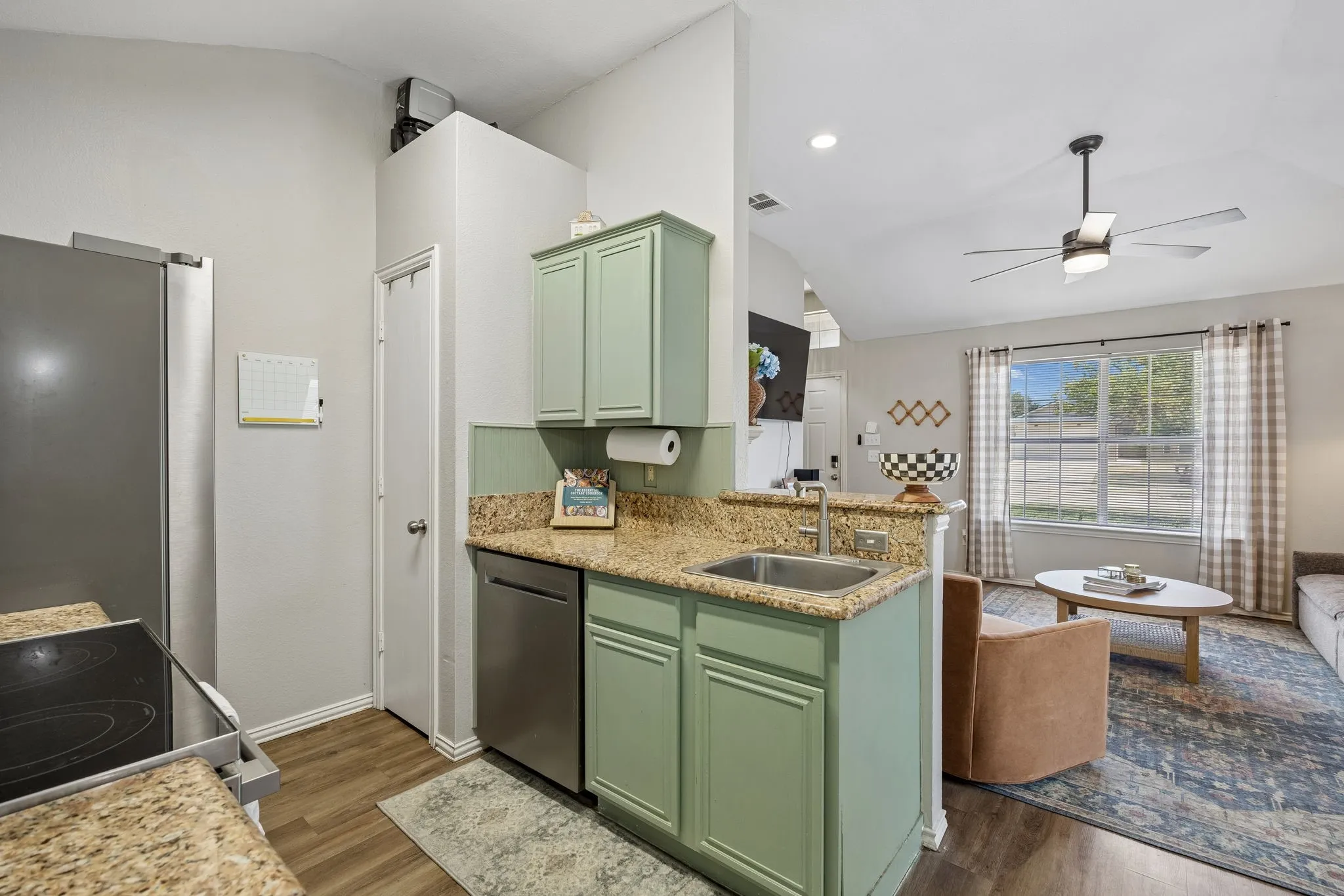 Kitchenette with granite-style countertops, stainless steel sink, and wood-finish flooring