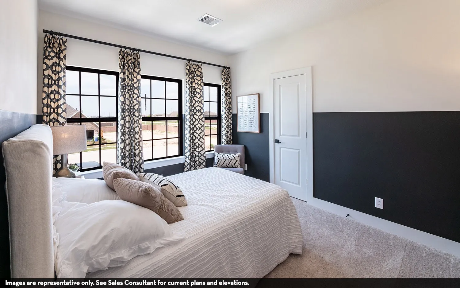 Three large windows with black frames, two-tone wall treatment, and white interior door with black hardware
