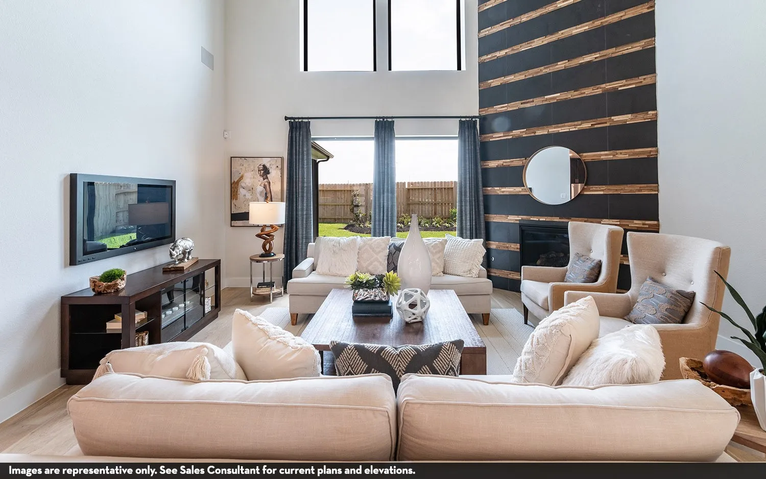 High ceilings, wood-finish flooring, two-story windows, a fireplace with a textured surround, and dark-framed windows