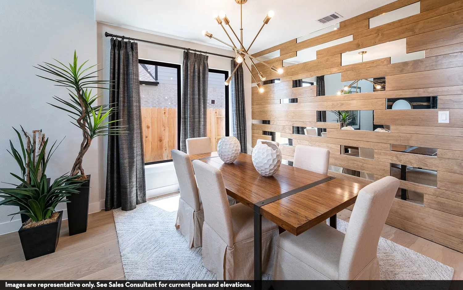 Wood-finish flooring, accent wall with wood-finish panels and reflective inserts, contemporary chandelier, and large windows with dark drapery