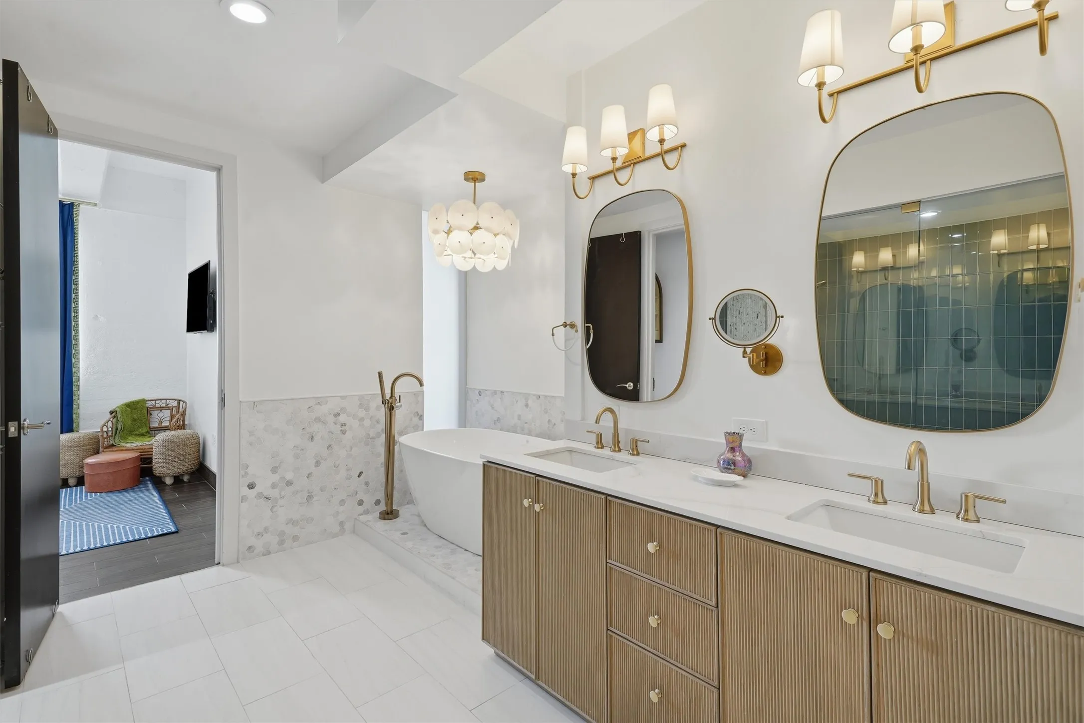 Primary ensuite bath showing seamless flow directly into the main bedroom. Features a fluted wood double vanity with marble counters.