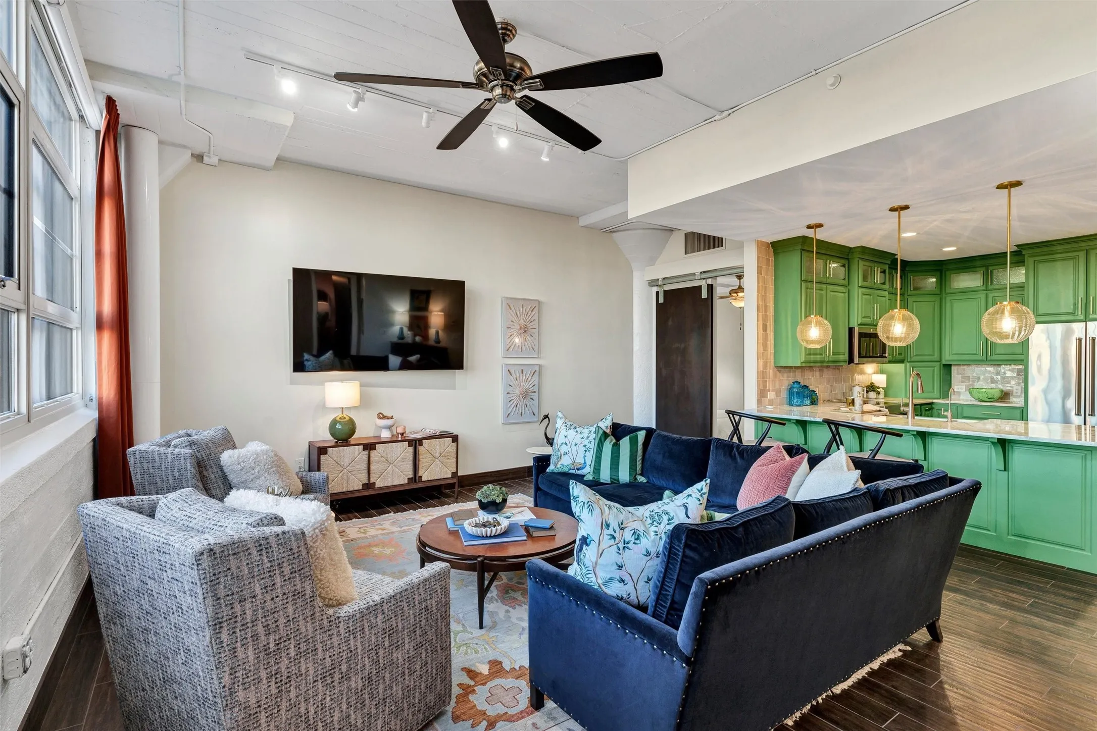 Open-concept layout seamlessly connecting the main living space to a stunning kitchen with vibrant green cabinetry. An expansive breakfast bar create an effortless flow for everyday living and entertaining.