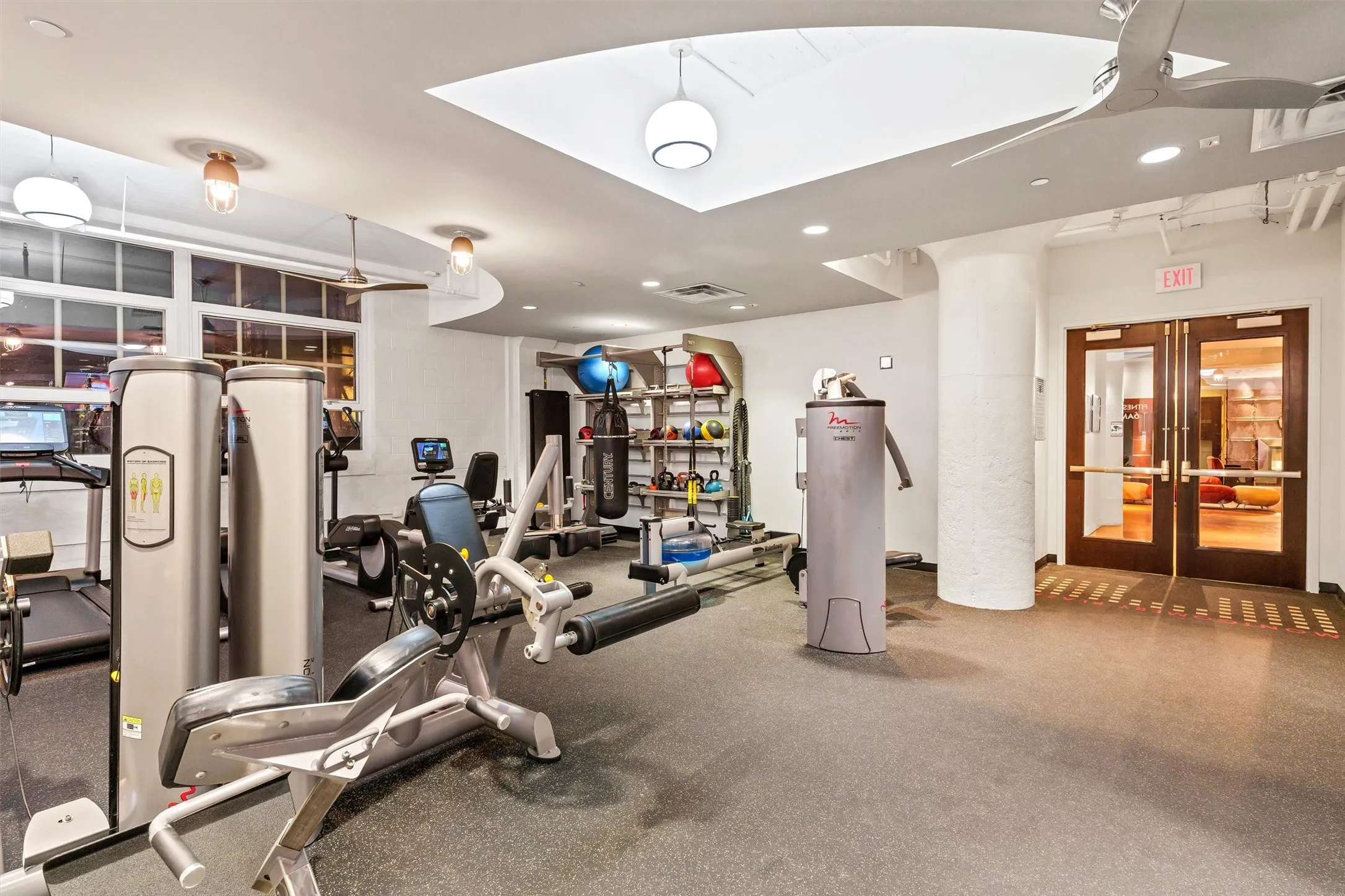 Fully equipped private resident fitness room featuring treadmills, weight-training machines, a rower, punching bag, and a medicine ball rack, offering a complete gym experience without leaving the building.