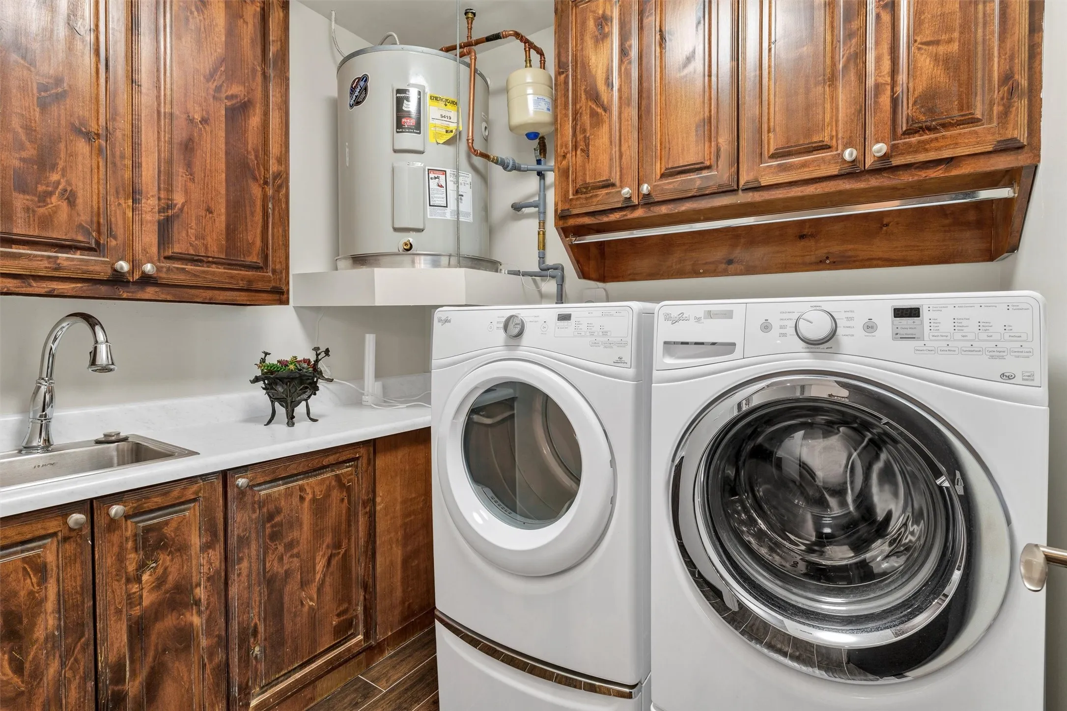 High-function laundry setup complete with a built-in utility sink, folding counter area, hanging rod, and storage drawers/cabinets.