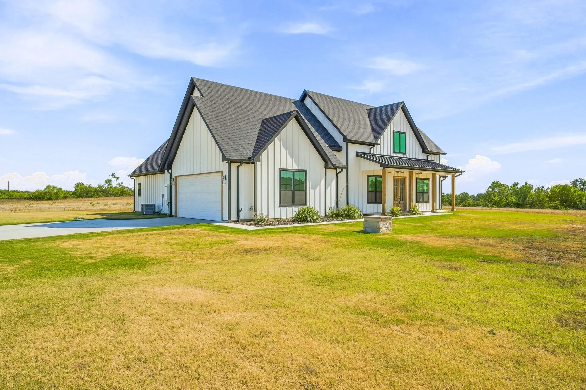 Modern farmhouse exterior with vertical white siding, black-framed windows, and a covered porch with wooden posts