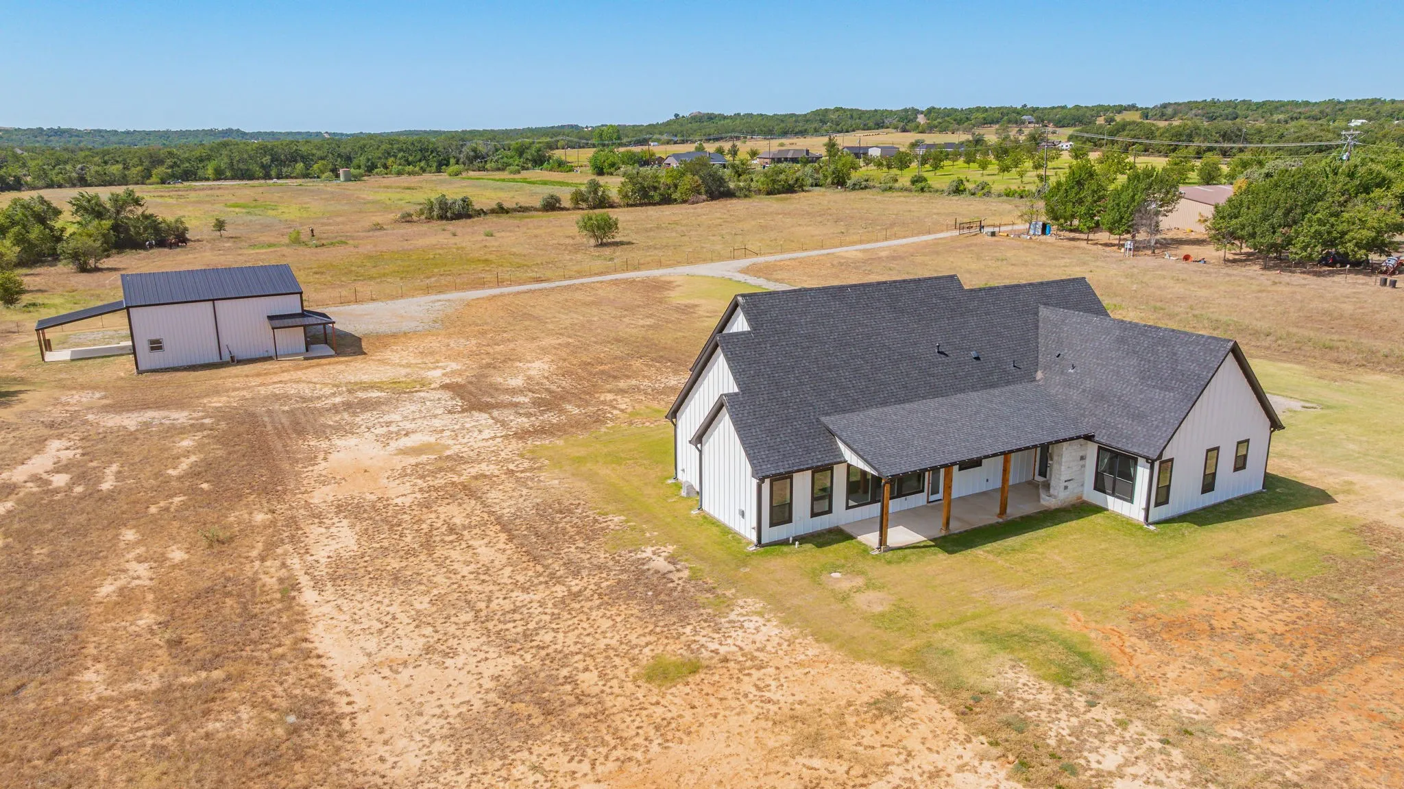 Modern farmhouse-style residence featuring a dark shingle roof and white vertical siding