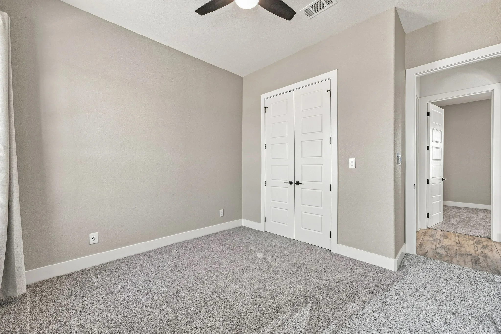 Carpeted flooring, contemporary bi-fold doors, modern ceiling fan with light, neutral wall paint, and white trim