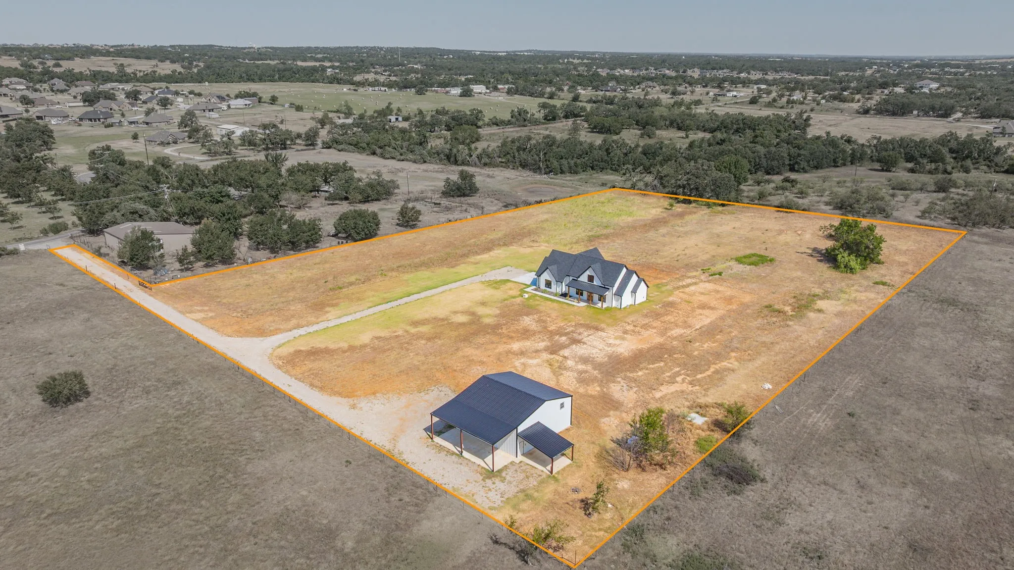Contemporary main residence, separate ancillary building, gravel drive, extensive land parcel, and natural landscaping