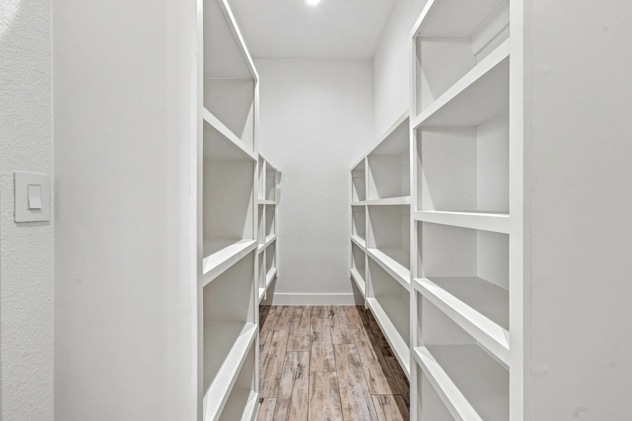 Built-in shelving units, recessed ceiling lighting, textured wall finish, and wood-finish flooring