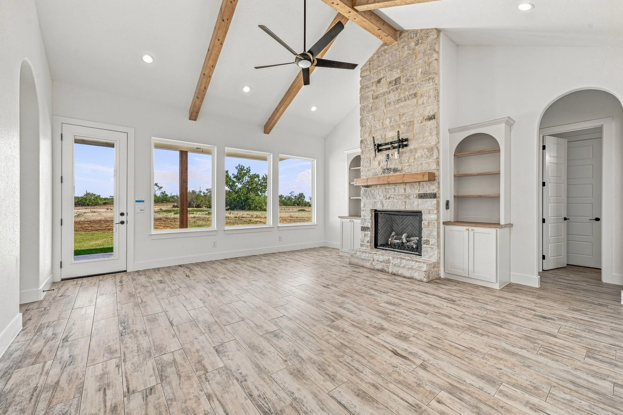 Vaulted ceiling with exposed wood beams and a large ceiling fan