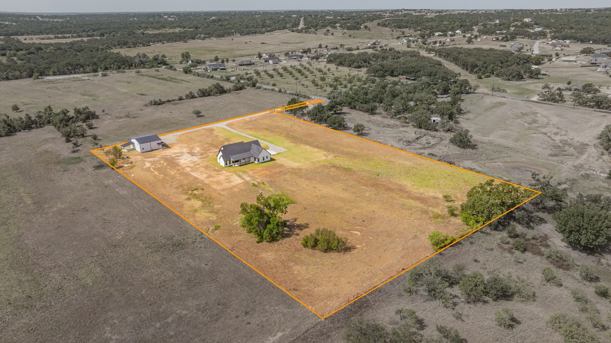 Expansive property featuring a contemporary residence, a detached auxiliary building, and mature trees