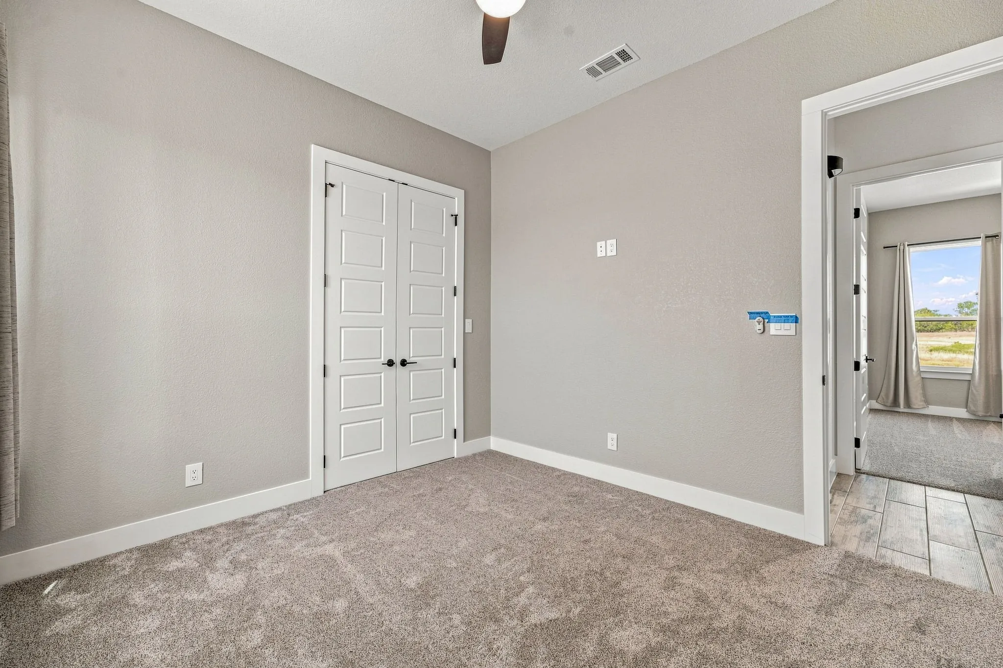 Carpeted room featuring a ceiling fan, white trim, and a double door entry