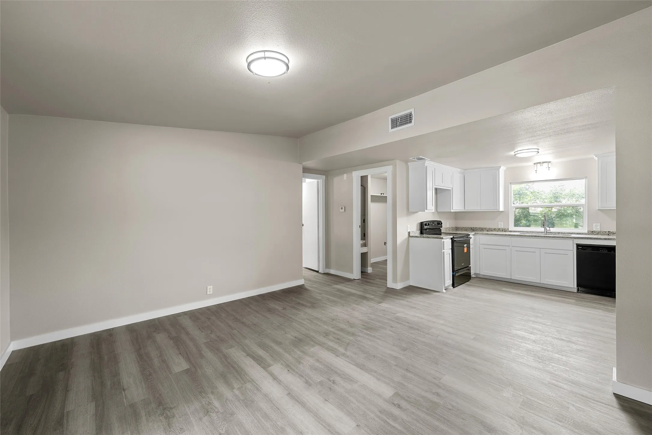 Spacious room with wood-finish plank flooring, neutral wall tones, and recessed lighting