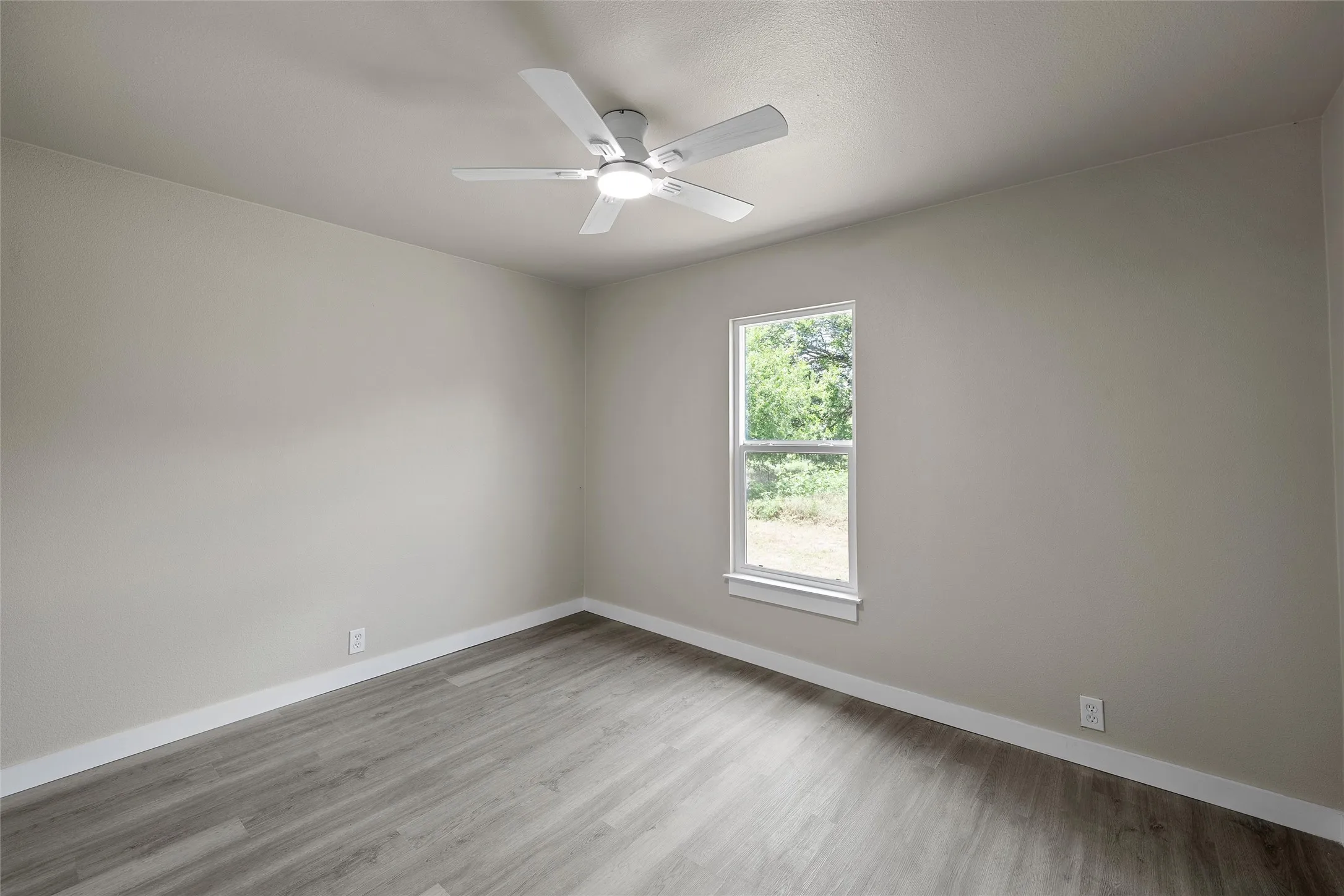 Wood-finish flooring, light-toned wall paint, white trim, white window frame, and a ceiling fan with integrated lighting