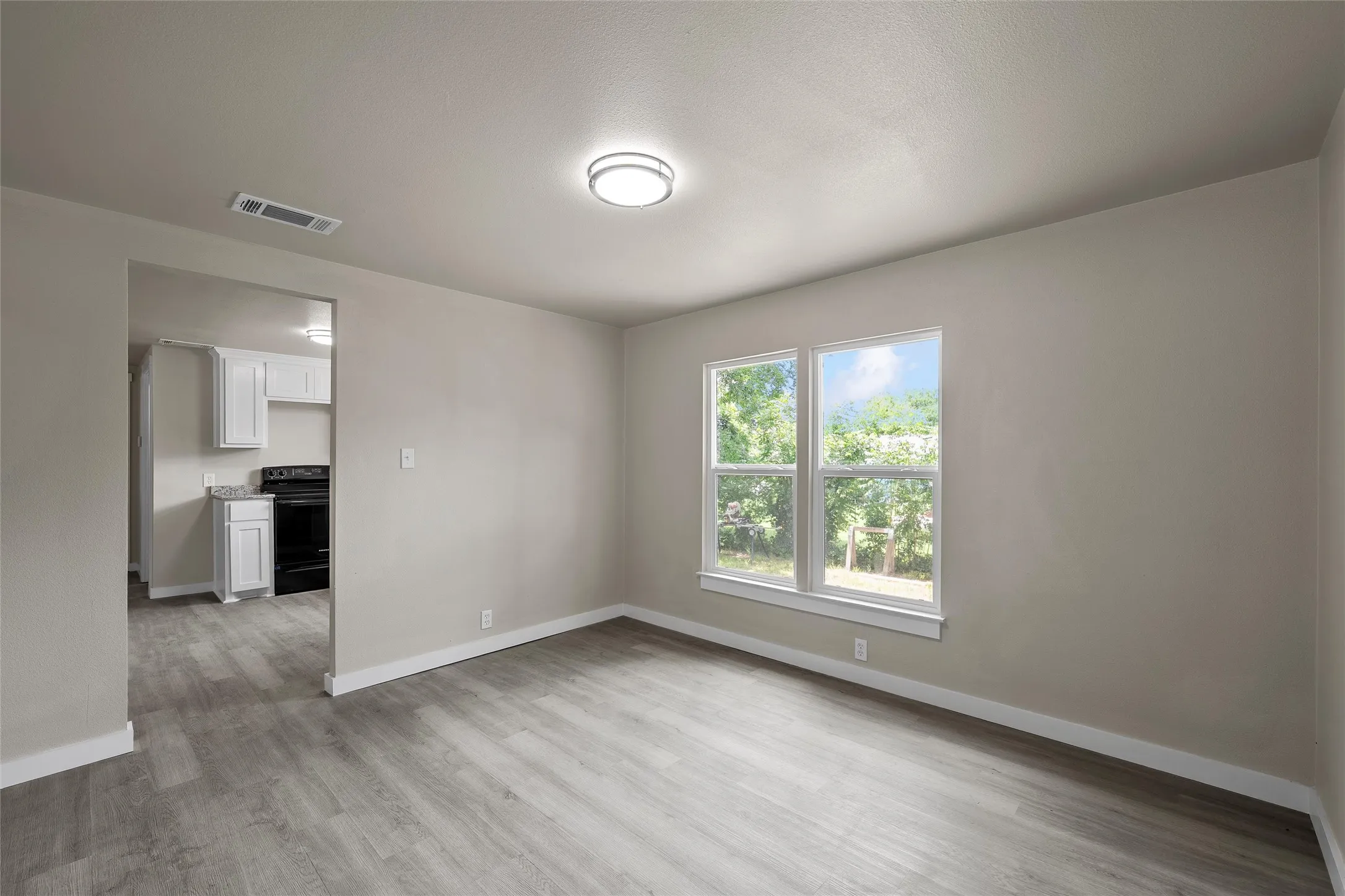 Spacious room with wood-finish plank flooring, neutral wall tones, and recessed lighting