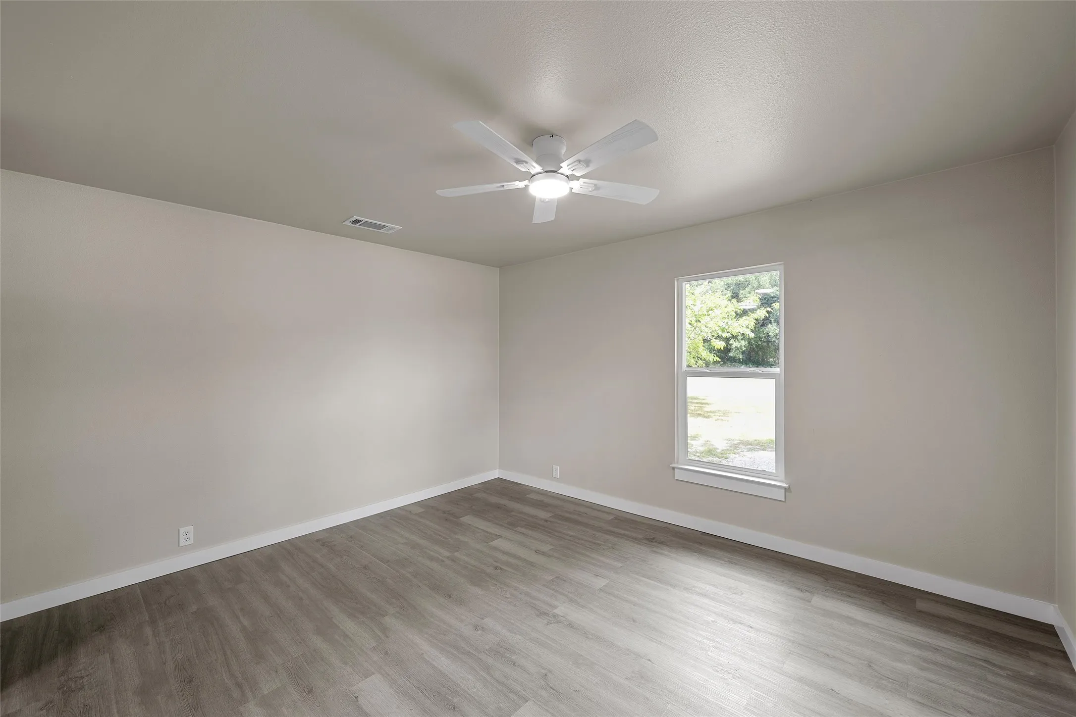 Neutral tone walls, wood-finish flooring, and a ceiling-mounted fan with integrated lighting