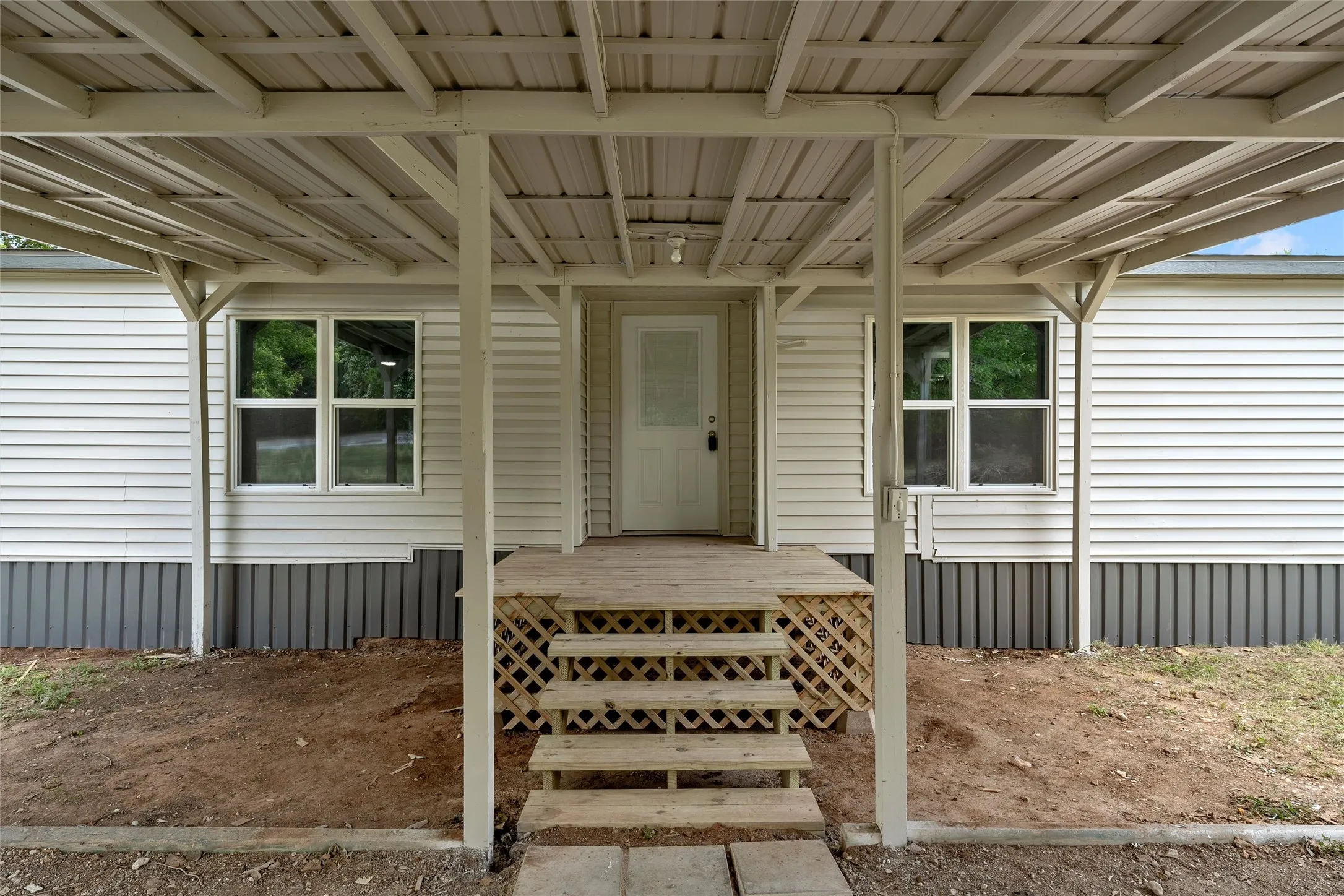 Covered entrance with a wood porch and steps