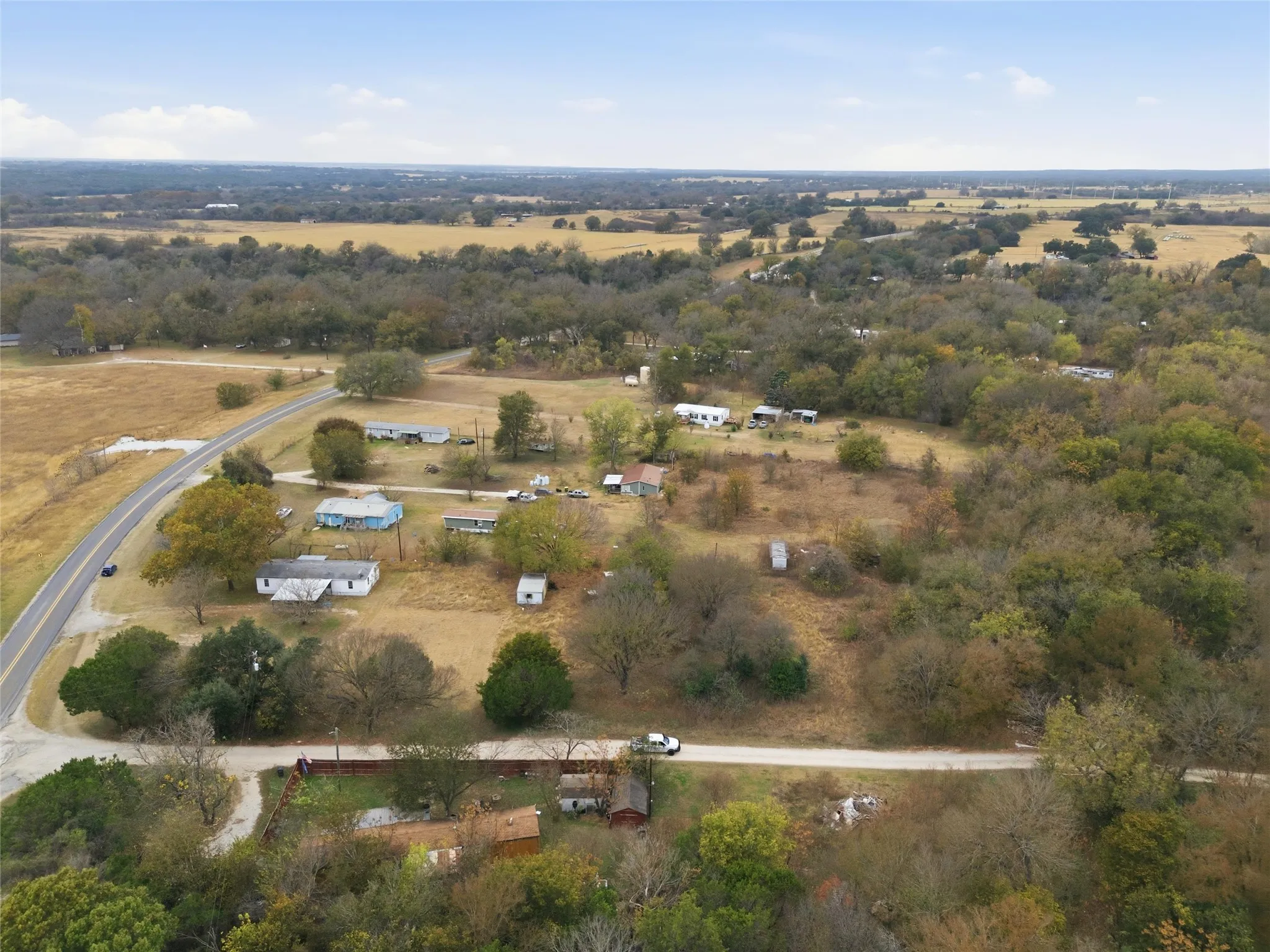 Expansive rural landscape featuring scattered residences, mature trees, and a paved roadway