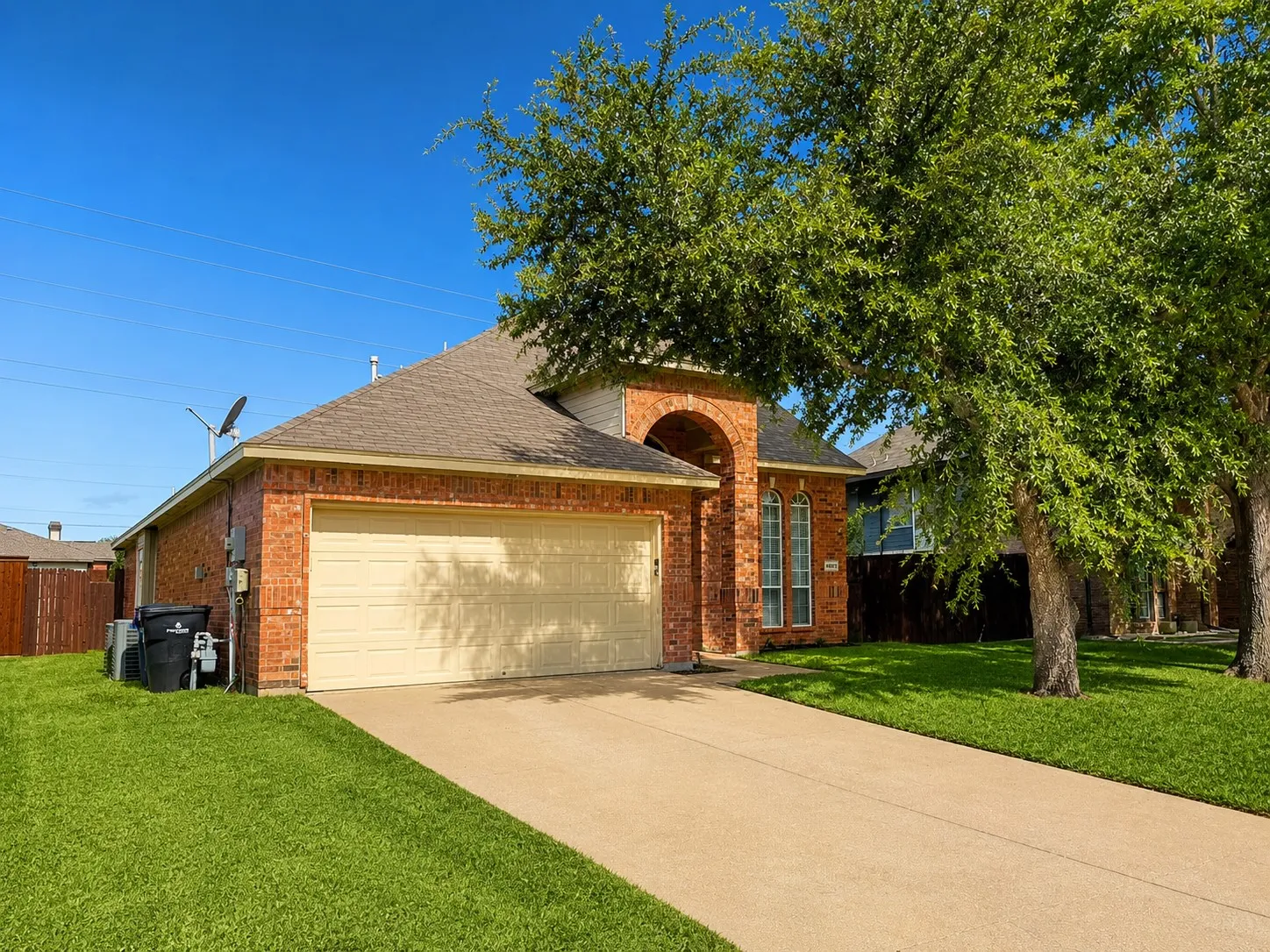 Brick exterior with a peaked roofline, an arched entryway, and a two-car garage