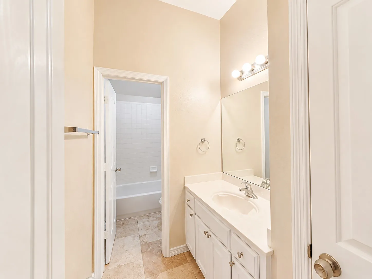 Bathroom featuring a single vanity with white cabinetry, a built-in sink, and a large wall-mounted mirror