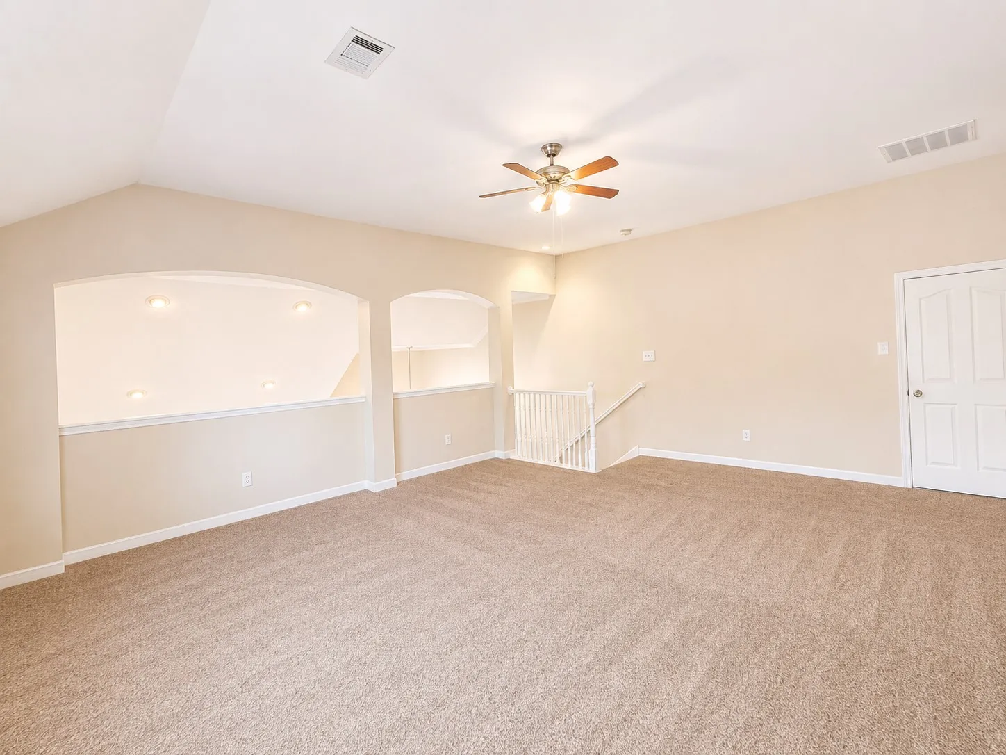 Vaulted ceiling, ceiling fan, carpeted flooring, interior balcony with arched openings, and white paneled interior door