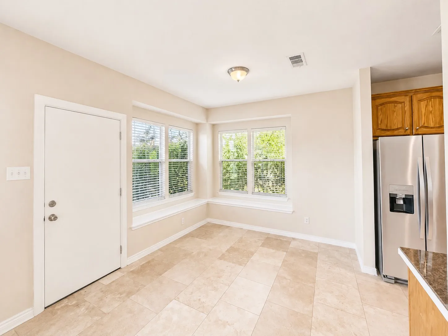Recessed lighting, wood-finish cabinetry, stainless steel refrigerator, and tiled flooring