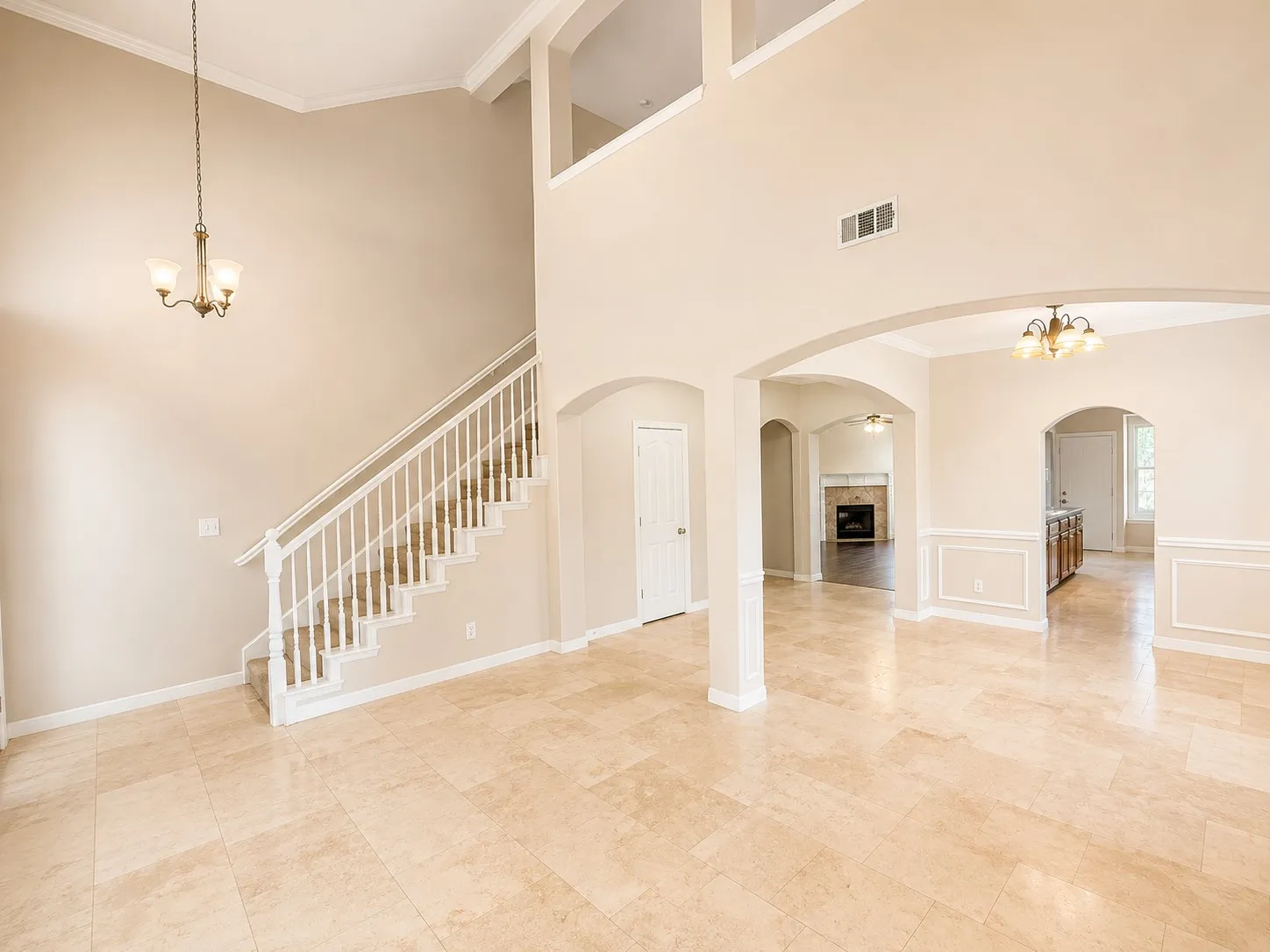 Two-story ceilings, arched doorways, a built-in staircase, tile flooring, and recessed lighting
