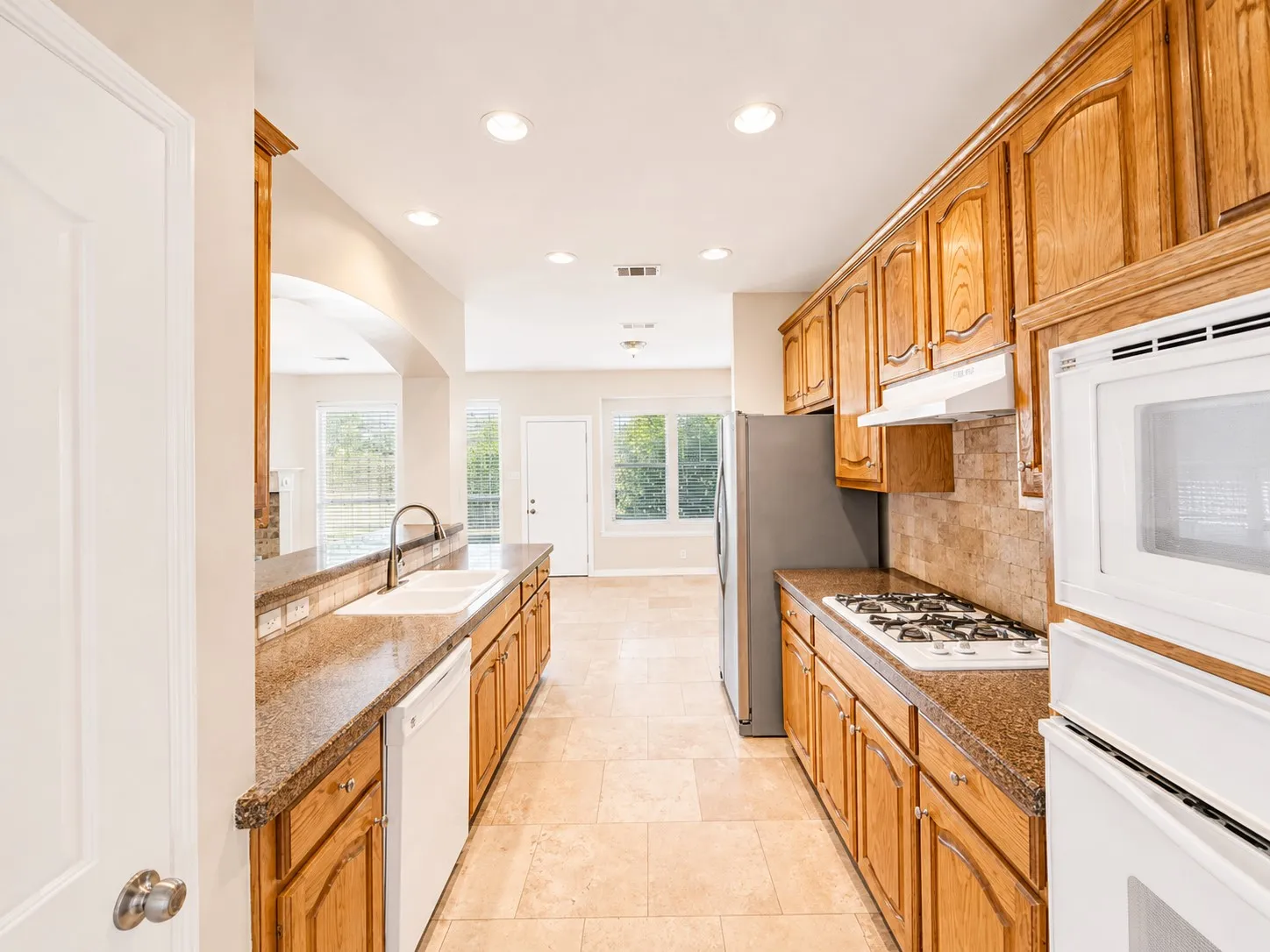 Kitchen featuring wood cabinetry, granite-style countertops, integrated gas range, and tile flooring