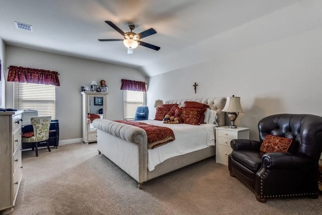 Carpeted flooring, vaulted ceiling, dual windows with blinds, and a built-in ceiling fan with light fixture