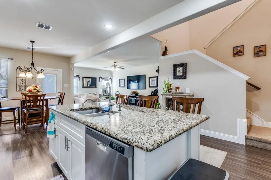 Kitchen island with granite countertop, stainless steel sink, and integrated dishwasher