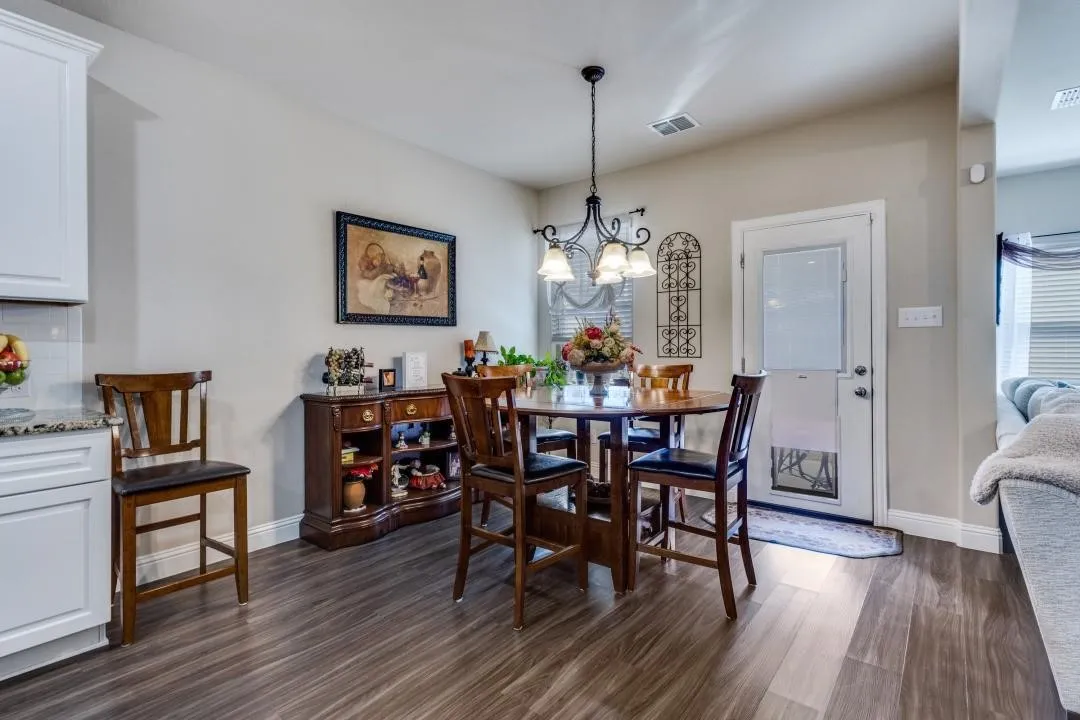 Wood-finish flooring throughout, white cabinetry with a light-toned countertop, and a chandelier-style lighting fixture