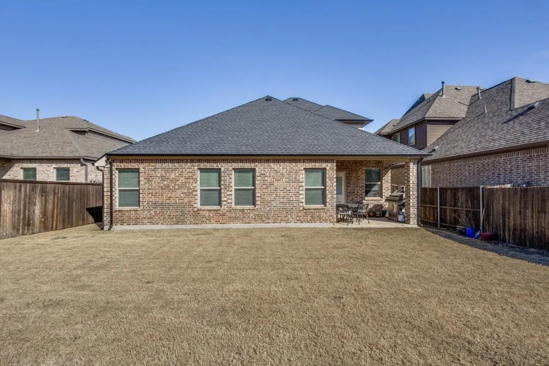 Brick exterior with multiple windows, covered patio, and fenced yard