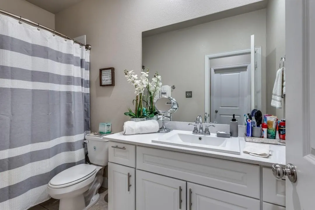 White vanity with an integrated sink, polished chrome faucet, and expansive wall-mounted mirror