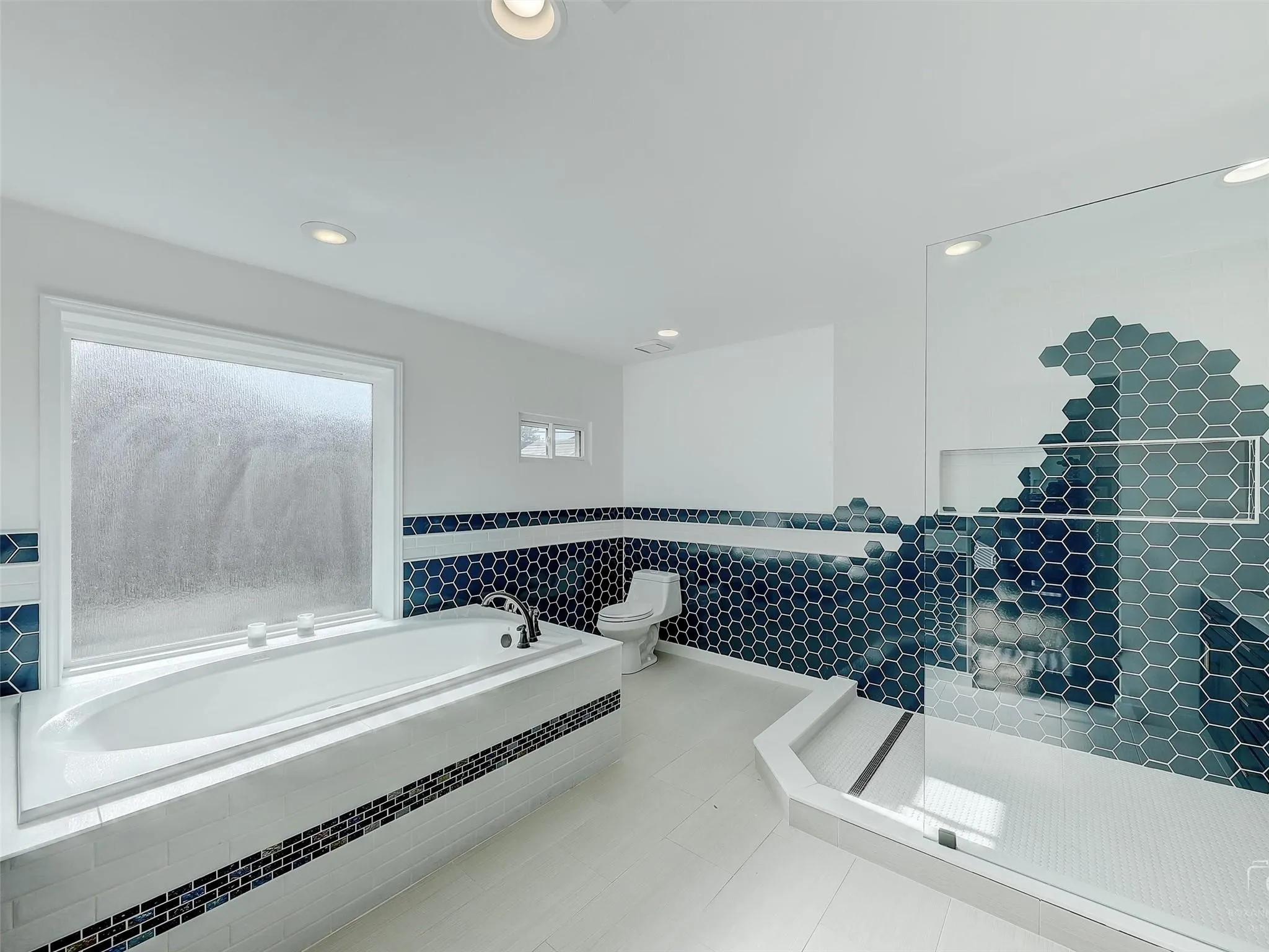 Bathroom featuring a healthy amount of sunlight, tile floors, and tile walls