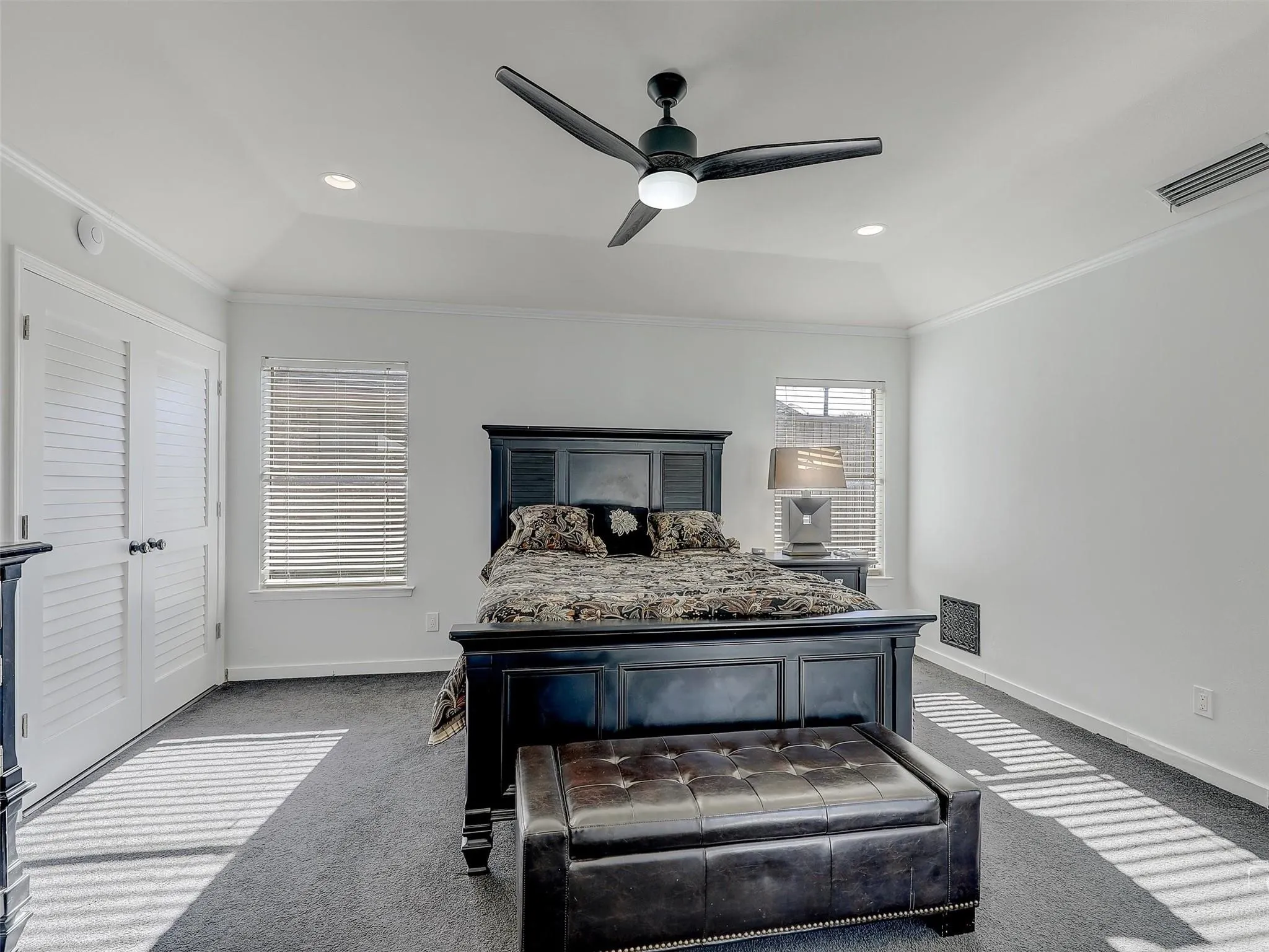 Carpeted bedroom featuring ornamental molding, vaulted ceiling, ceiling fan, and a raised ceiling