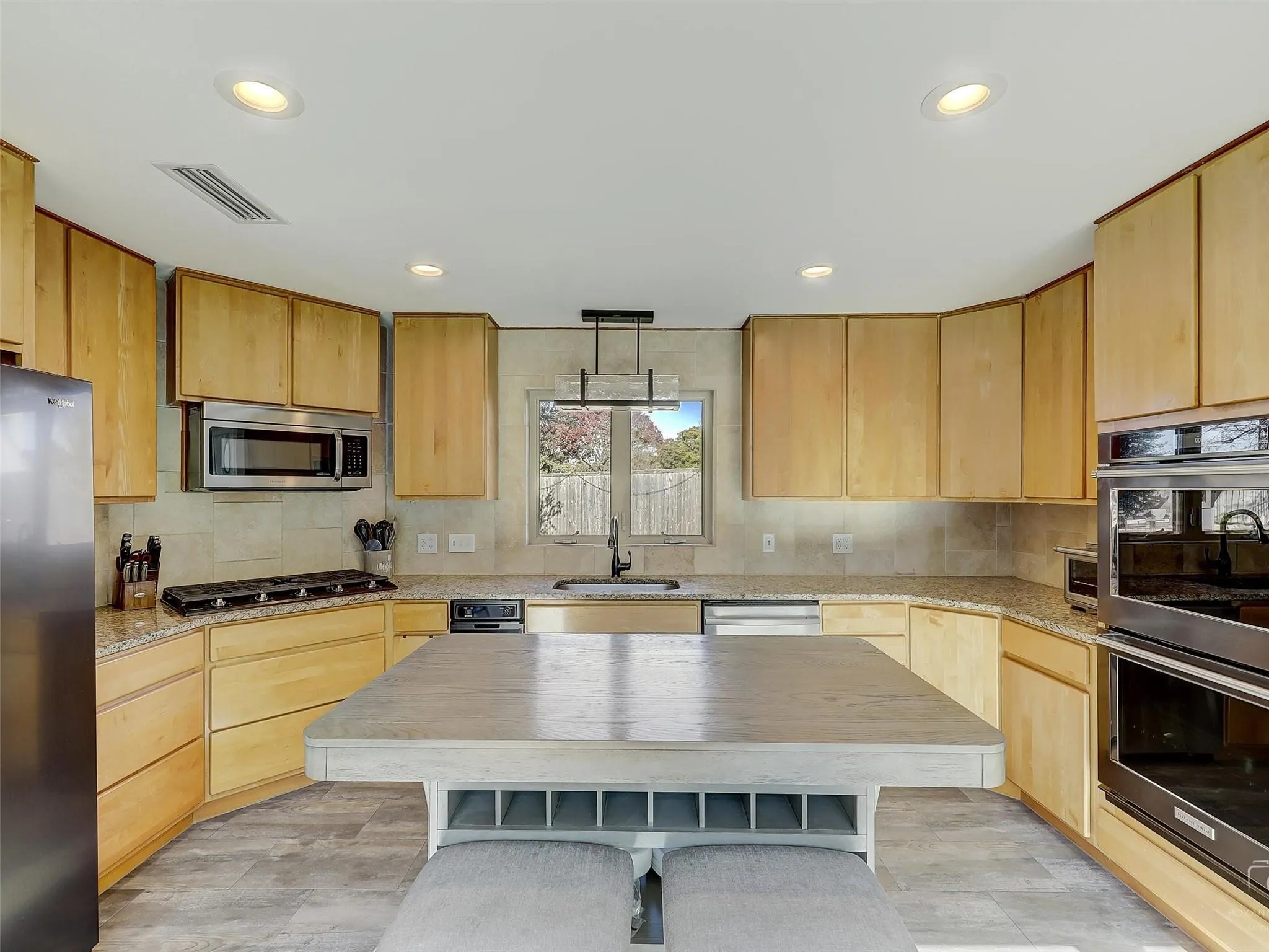 Kitchen featuring a center island, light brown cabinetry, sink, light wood-type flooring, and stainless steel appliances