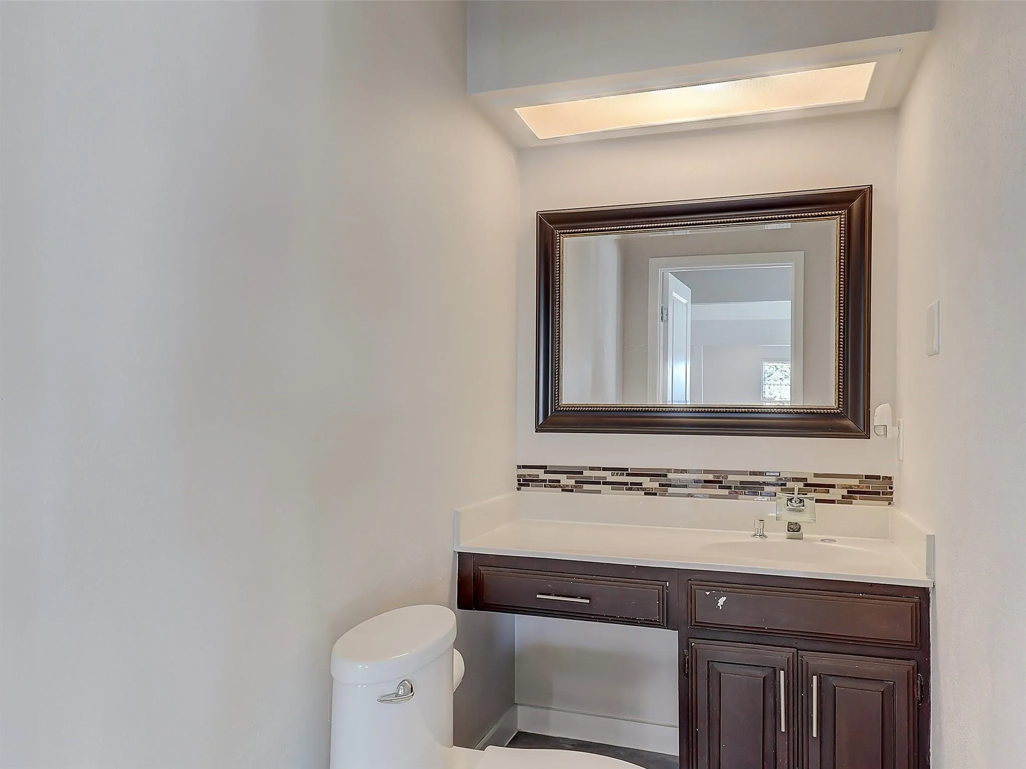 Bathroom featuring tasteful backsplash, vanity, and toilet