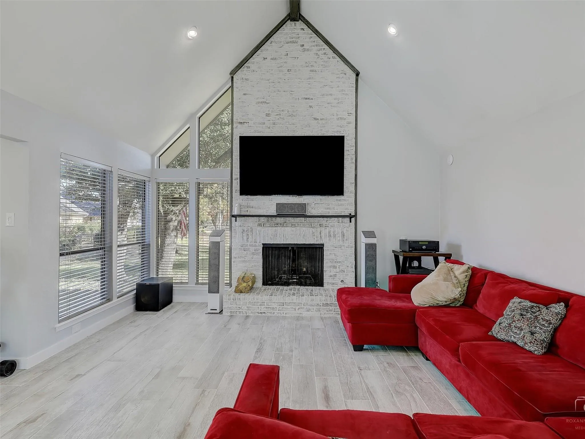Living room with a large fireplace, high vaulted ceiling, and hardwood / wood-style floors
