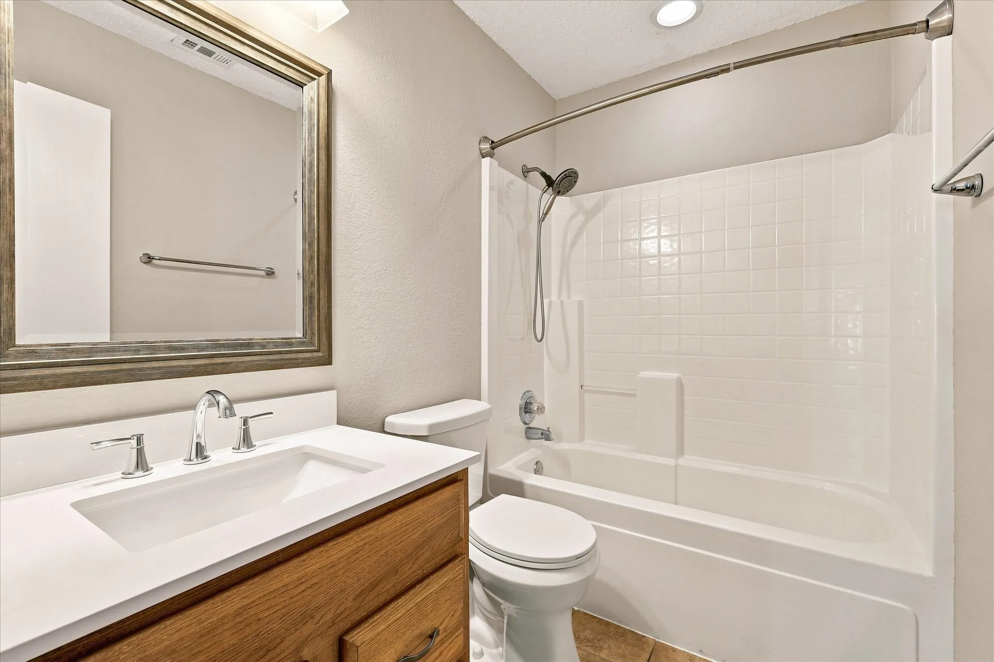 White vanity countertop with an integrated rectangular sink, chrome faucet, and framed mirror