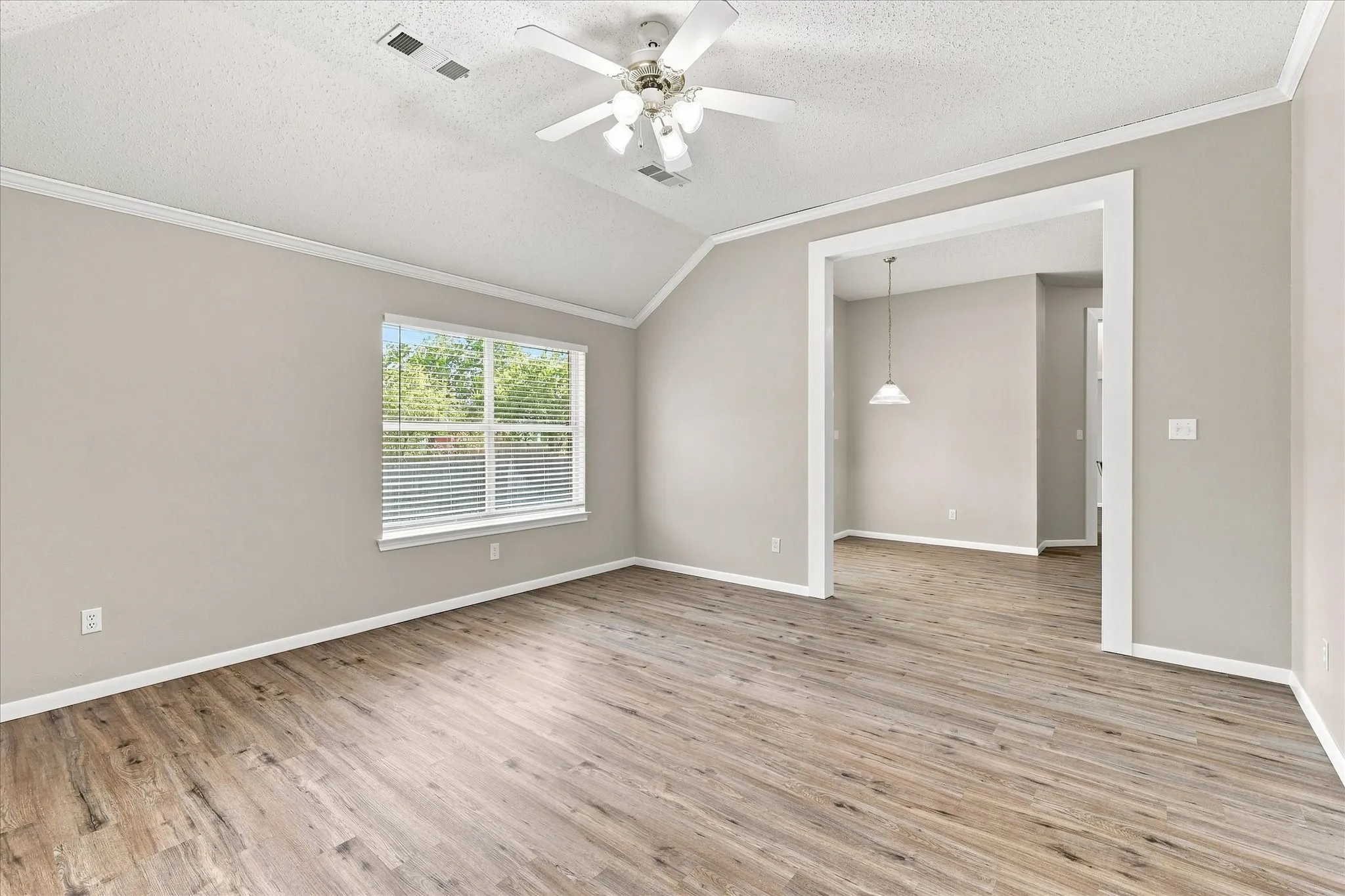 Vaulted ceiling with a ceiling fan, wood-finish flooring, and a large window with blinds