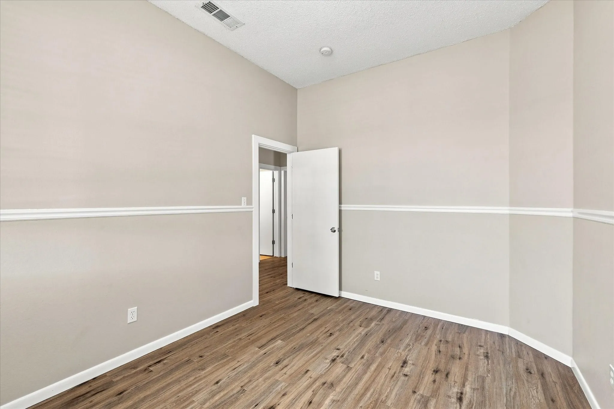 Wood-finish flooring, neutral wall paint, white trim, and a recessed ceiling light