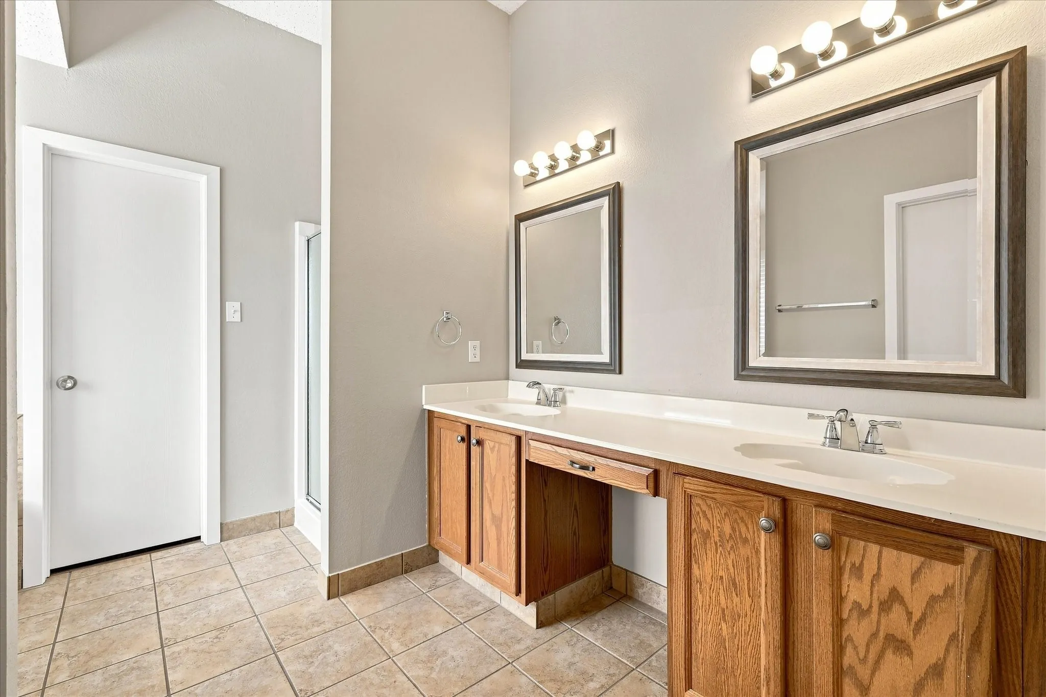 Dual vanities with integrated sinks, wood cabinetry, framed mirrors, and overhead bar lighting