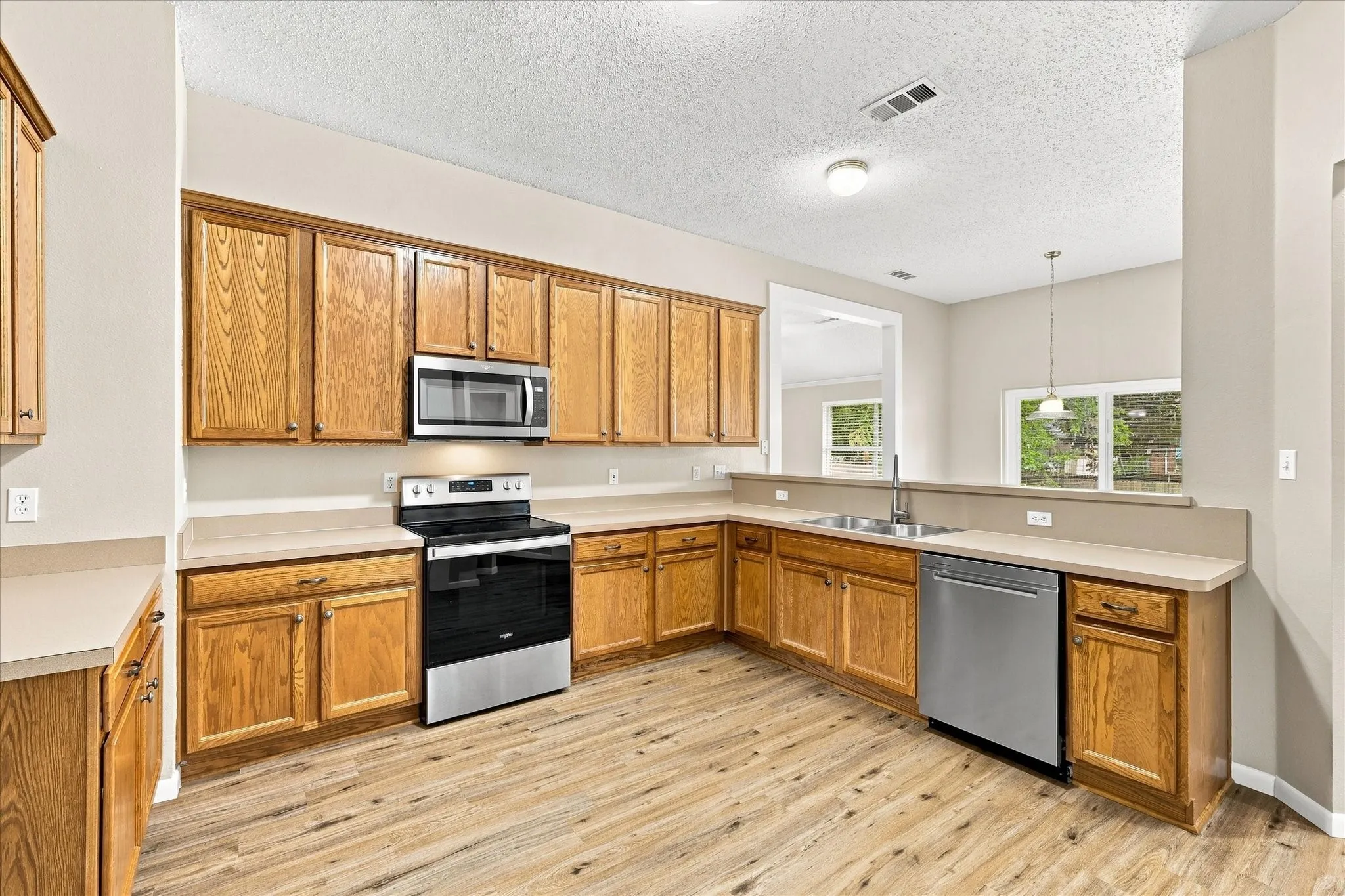 Wood-finish flooring, oak cabinetry, stainless steel appliances, and a double basin sink