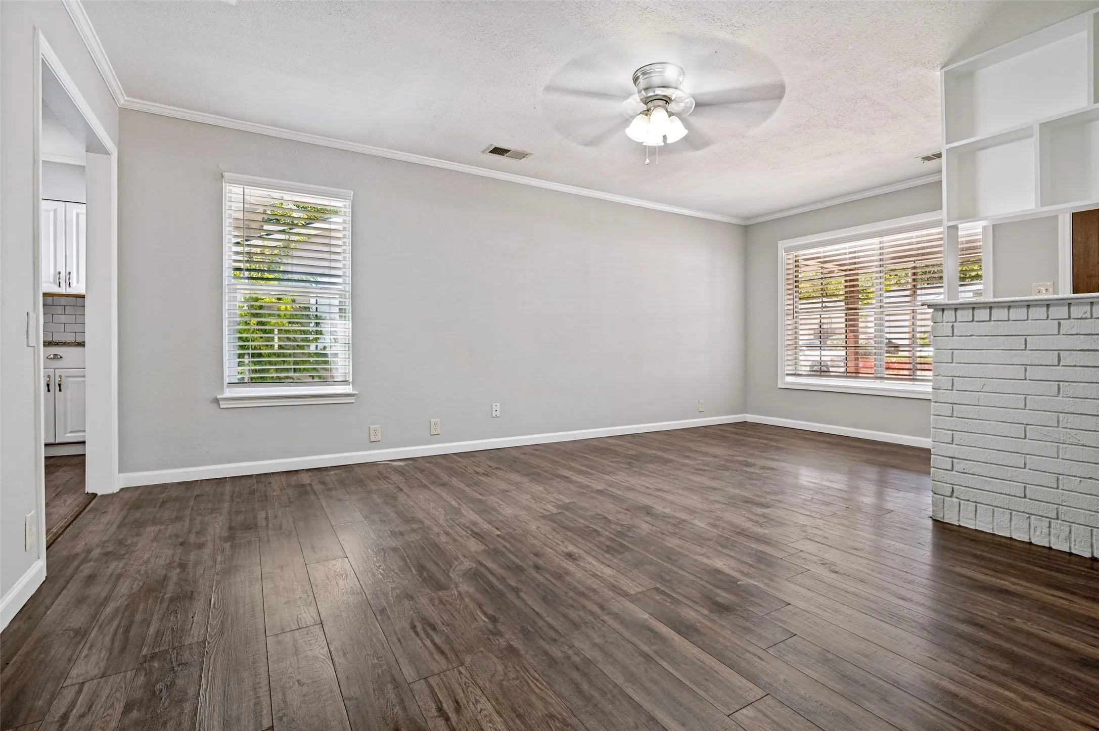 Spacious room with wood-finish flooring, white trim, and light gray walls