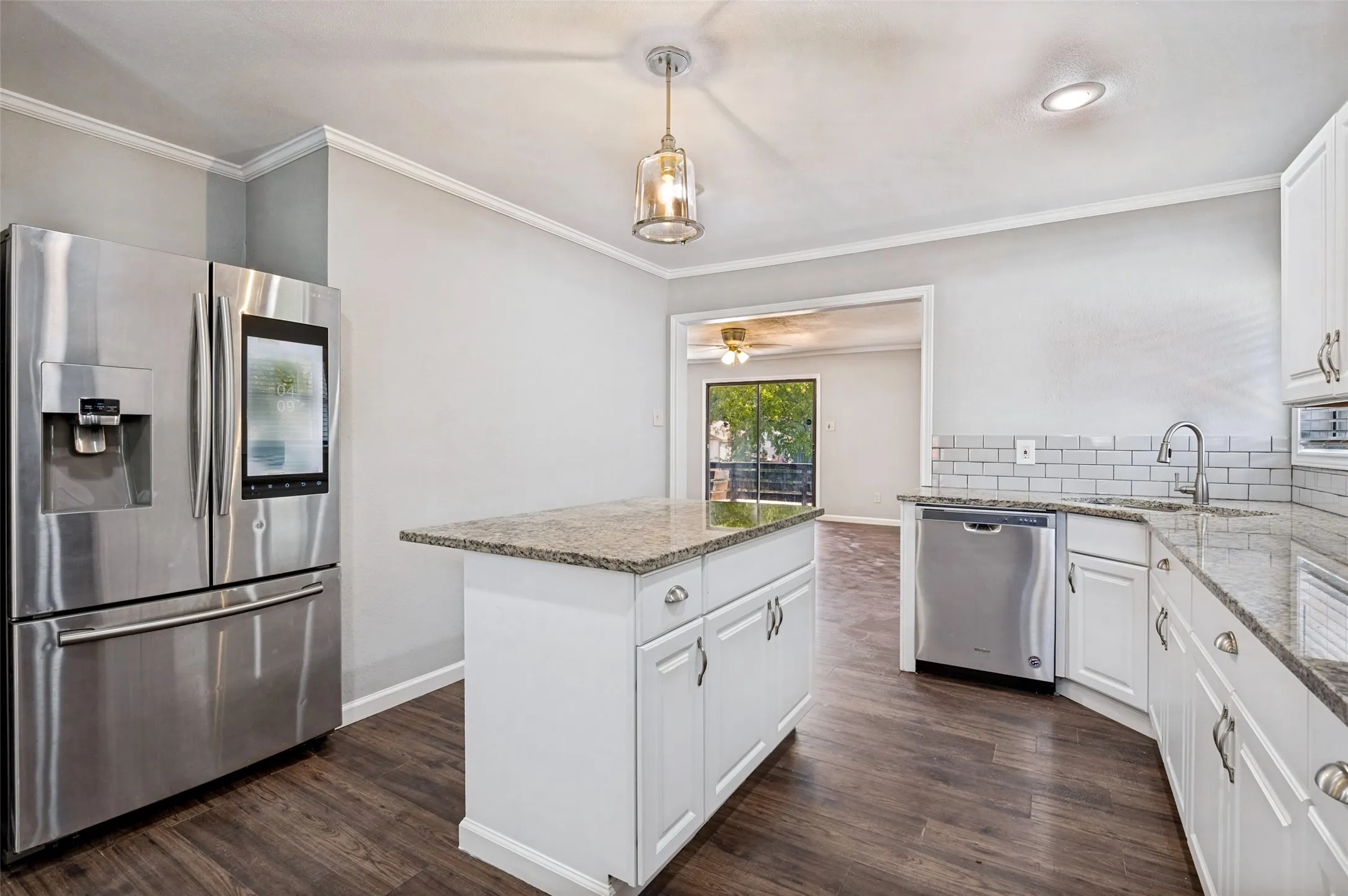 White cabinetry, stainless steel appliances, granite countertops, subway tile backsplash, and wood-finish flooring