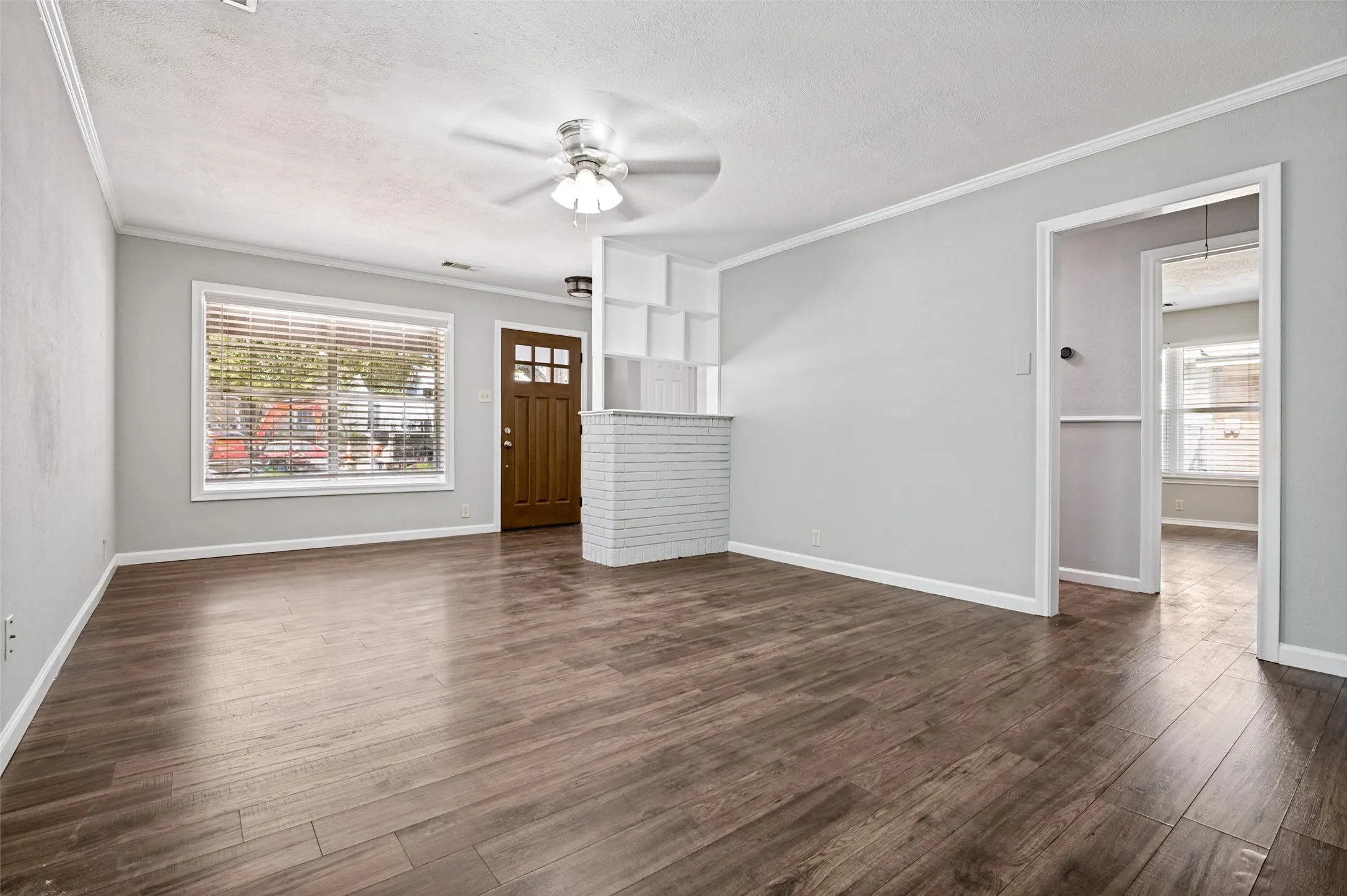 Wood-finish flooring throughout, light gray wall finishes, and a ceiling fan with integrated lighting
