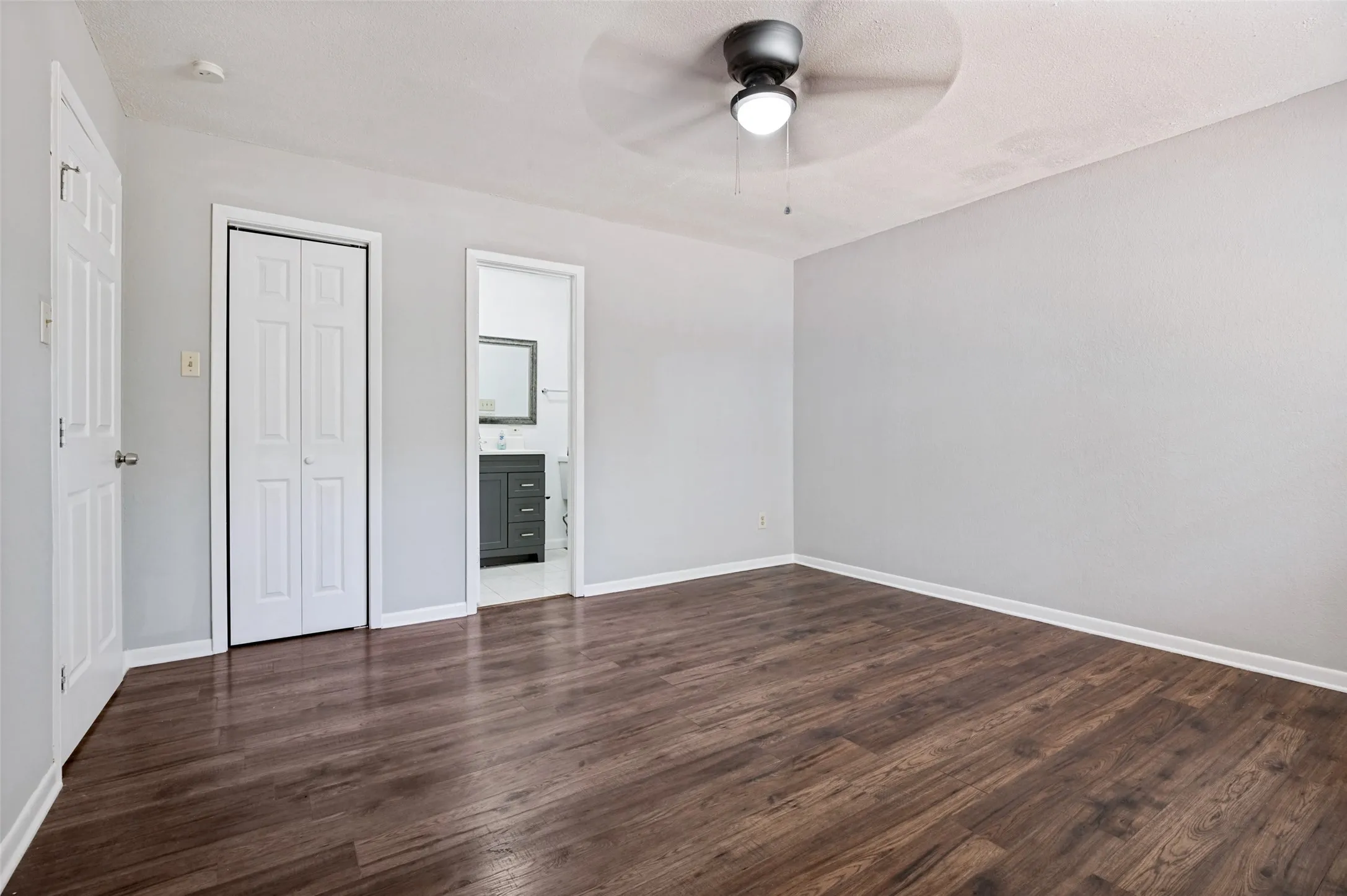 Wood-finish flooring, white bi-fold closet doors, ceiling fan with integrated lighting, white trim
